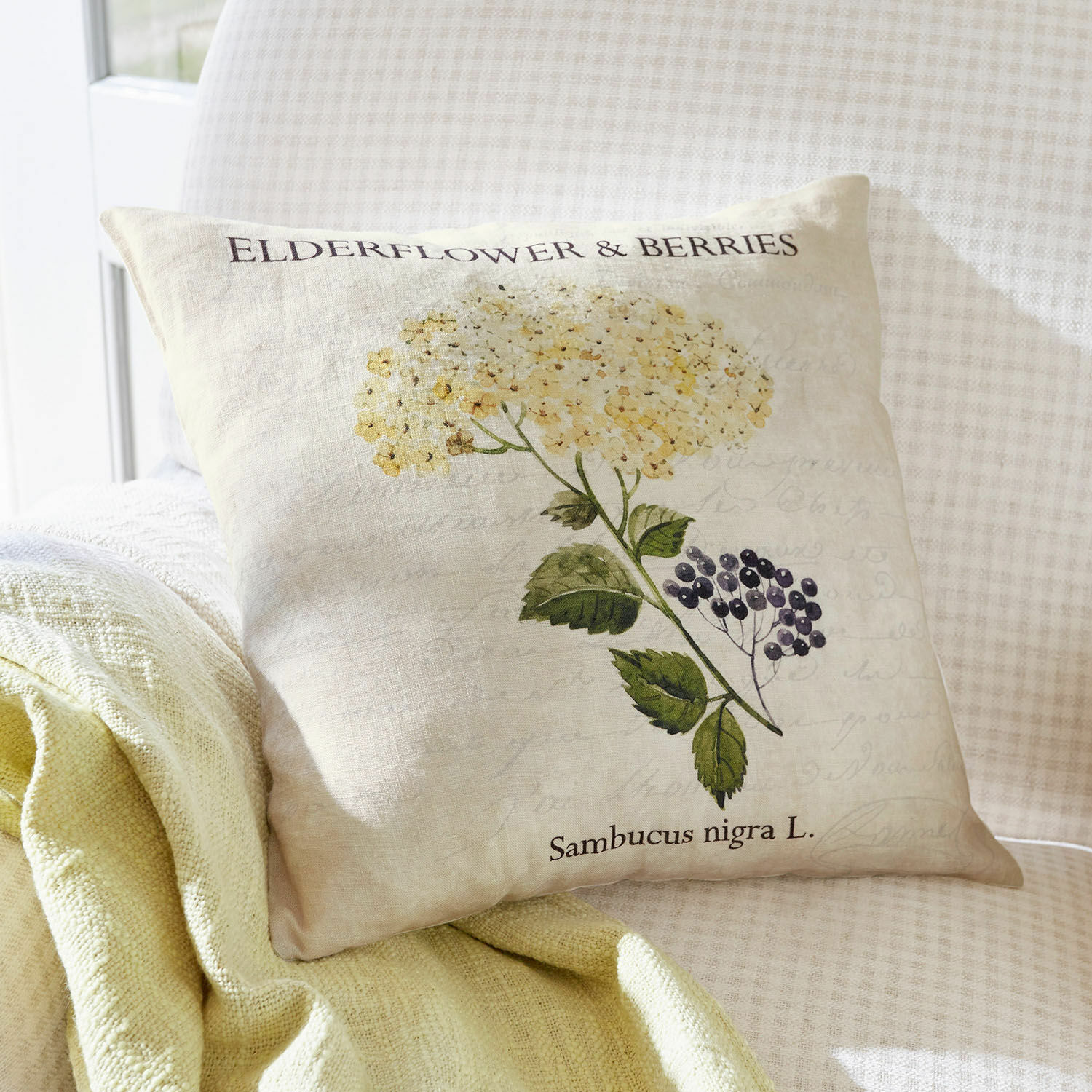 Kissenhülle Sambucus Beige Leinenkissen mit Druck von Holunderblüten und grünen Blättern, dekorativ im Wohnzimmer.