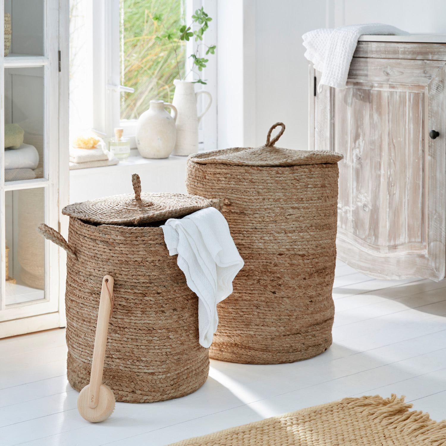 Zwei runde Wäschekörbe aus natürlicher Jute in Beige in einem hellen Badezimmer