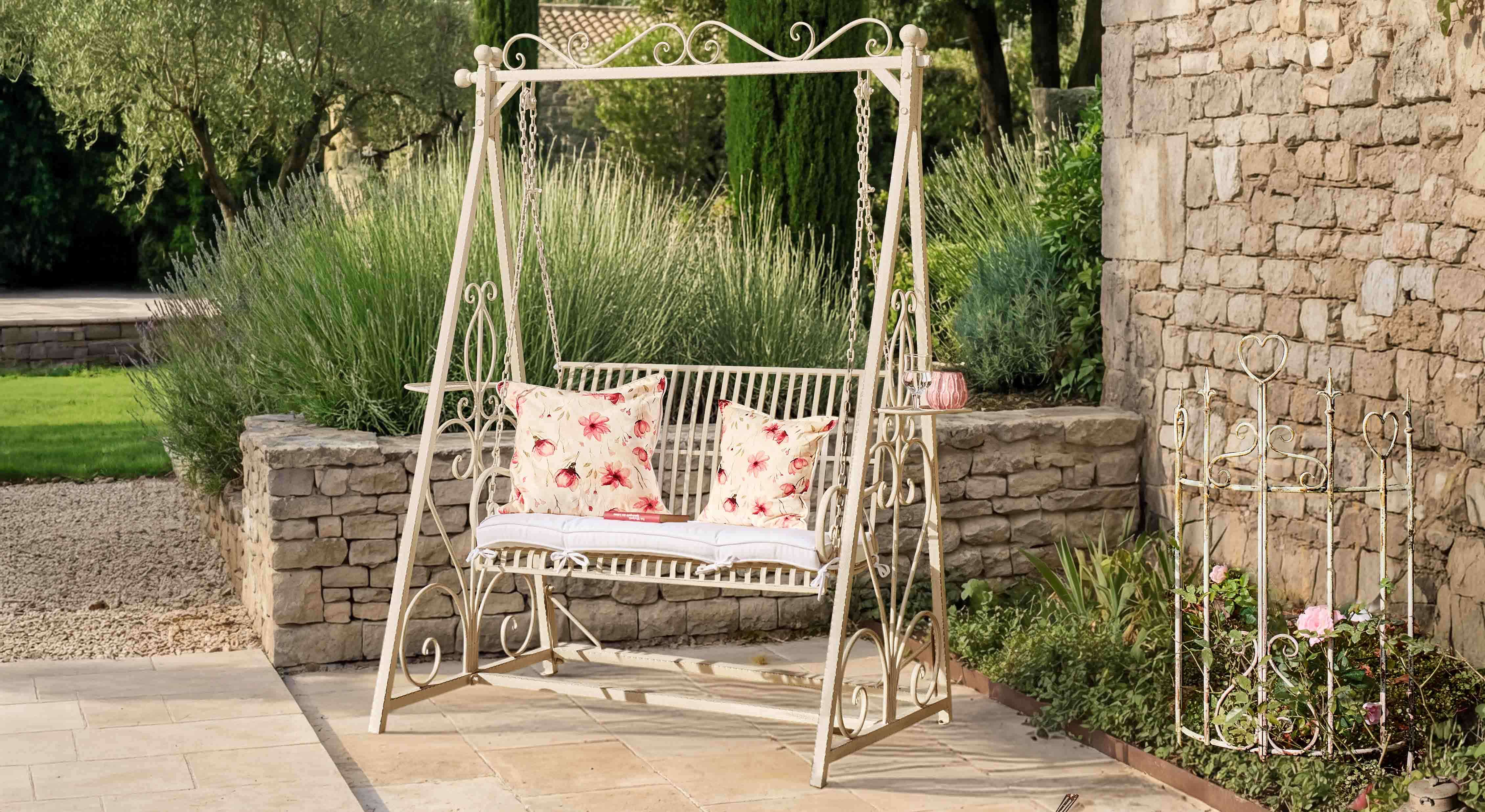 Metall-Gartenschaukel in Creme mit floralen Kissen auf Naturstein-Terrasse