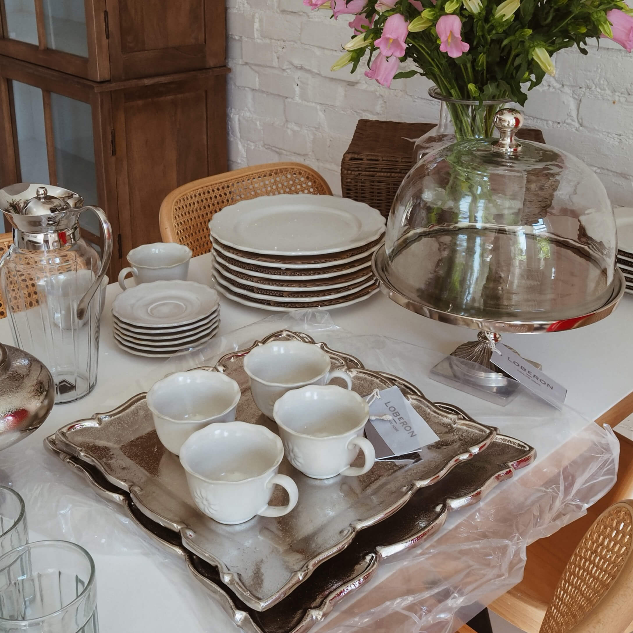 Weisses Porzellan mit Tassen und Tellern auf silbernem Tablett, Slow-Living-Tischdekoration