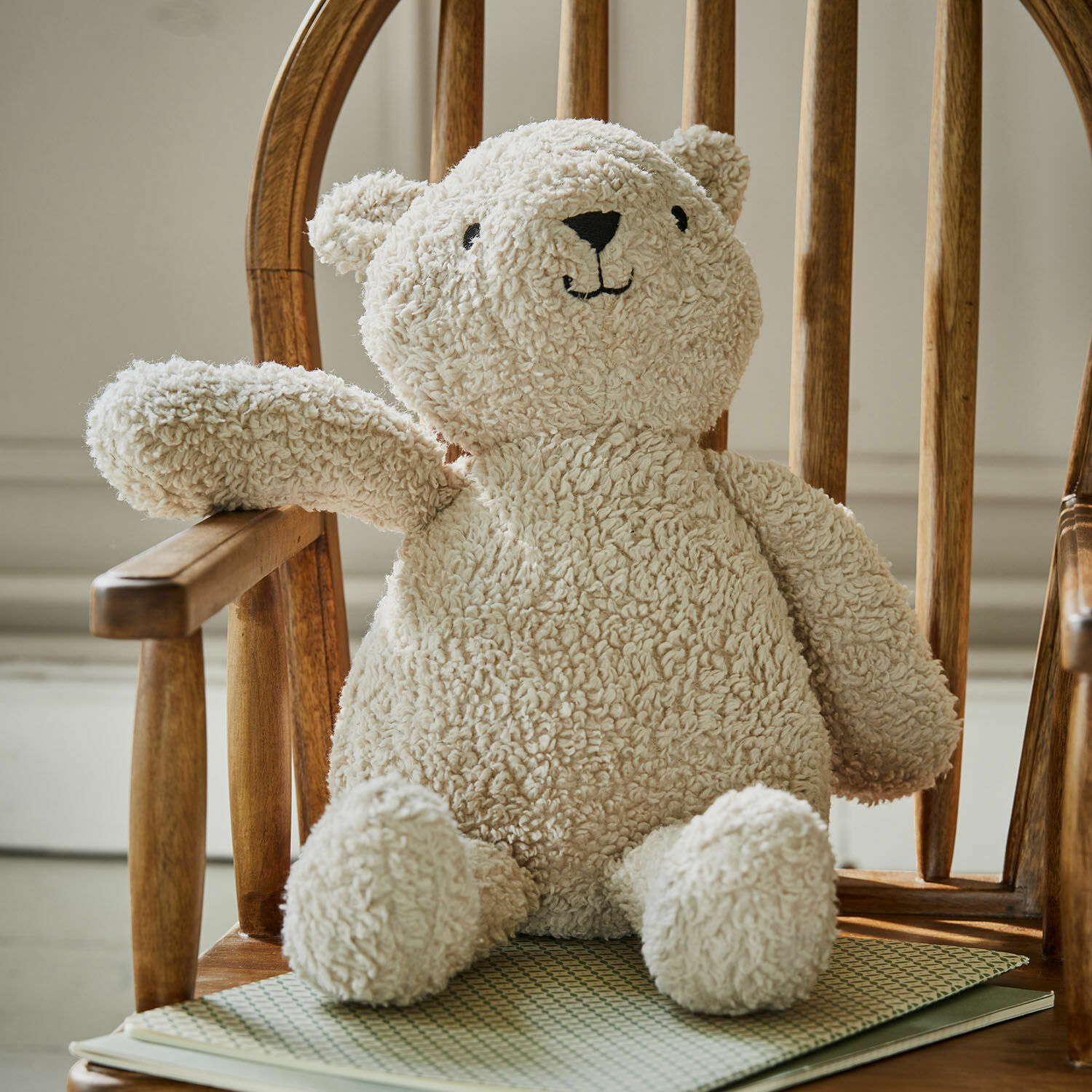 Stofftier Fuffino Weicher Teddybär aus cremefarbenem Plüsch auf Holzstuhl, Kinderzimmerdekoration
