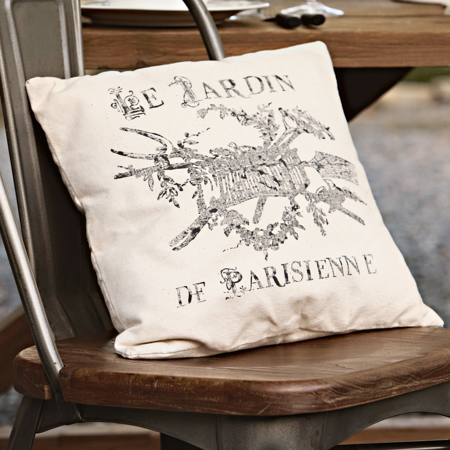 Kissen Le jardin Beiges Dekokissen aus Baumwolle mit schwarzem Vintage-Druck auf rustikalem Holzstuhl