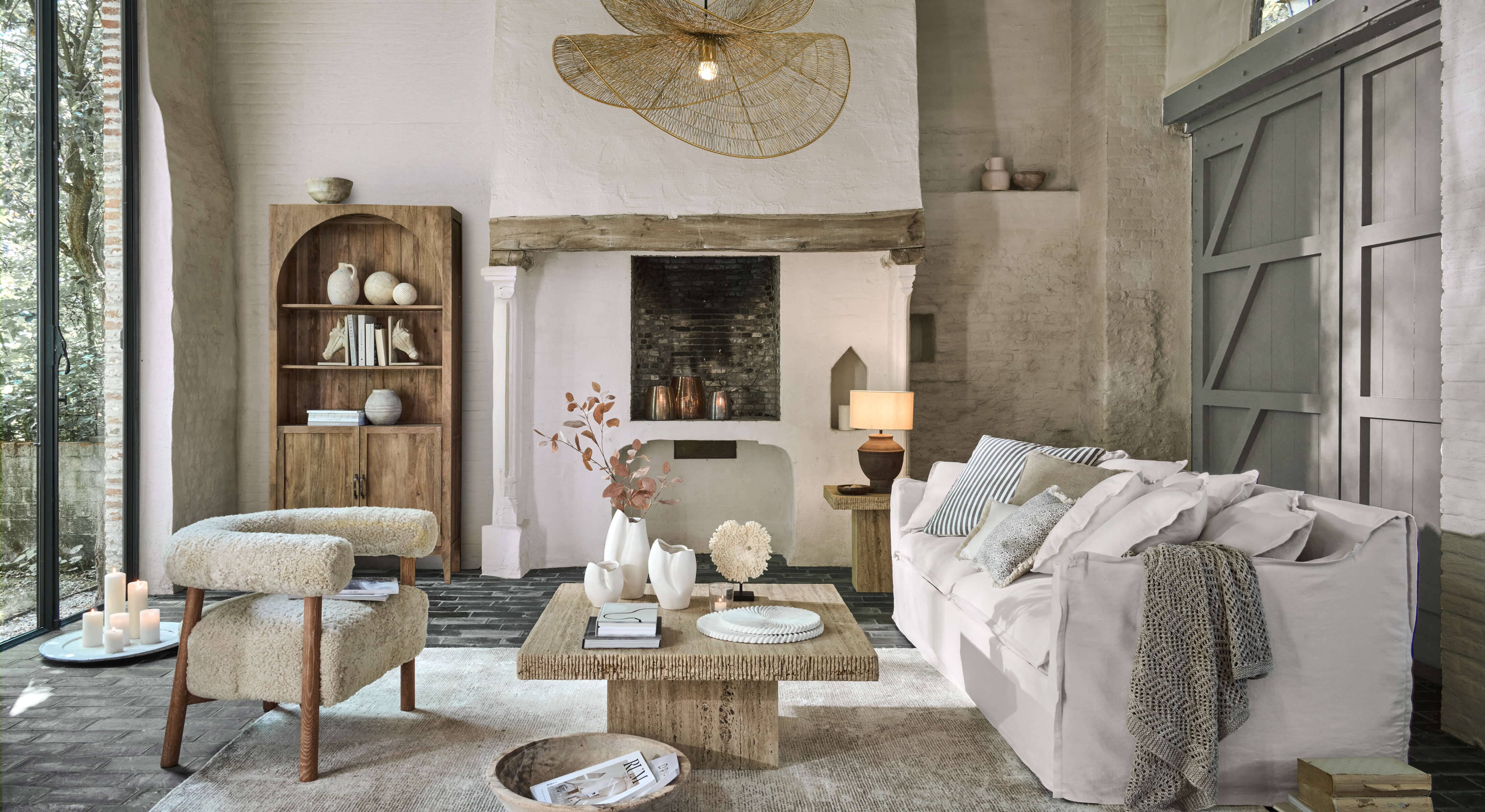 Gemütliches Wohnzimmer mit weissem Sofa, beigem Stoffsessel und Holzcouchtisch auf hellem Teppich