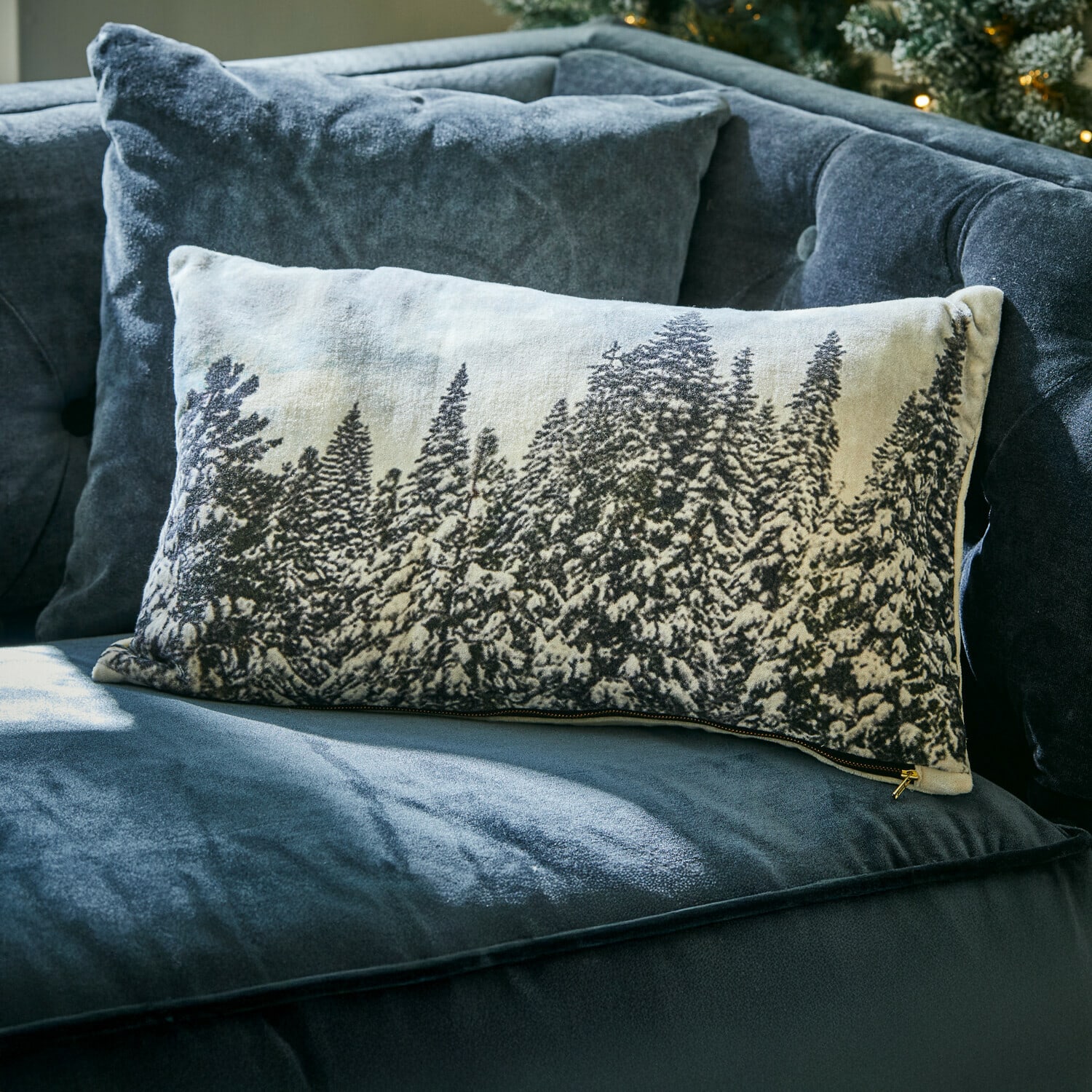 Kissenhülle Silver Creek Rechteckiges Dekokissen mit Winterwald-Motiv auf hellem Stoff auf dunkelblauem Samtsofa