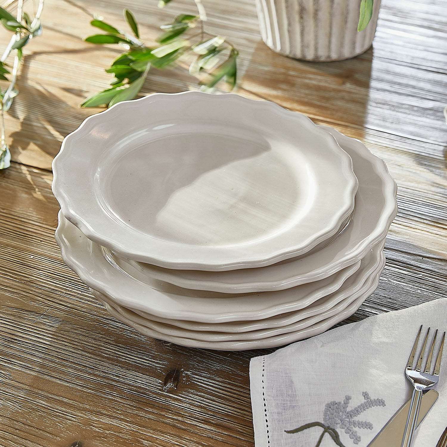 Teller 6er Set Mallevesse Set aus weissen Keramiktellern mit wellenförmigem Rand auf Holztisch mit Serviette und Besteck