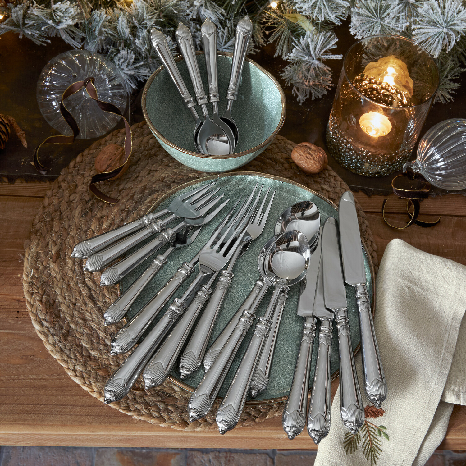 Besteck Gasharba Set silberner Edelstahlbestecke auf grünem Teller und Schale mit weihnachtlicher Dekoration