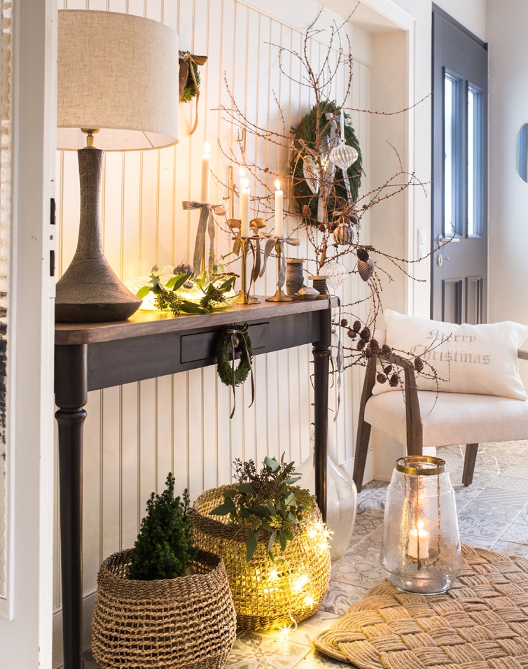 Gemütliches Interieur mit schwarzem Holztisch, Lampe sowie Weihnachtsdekoration aus Korb und Kerzen