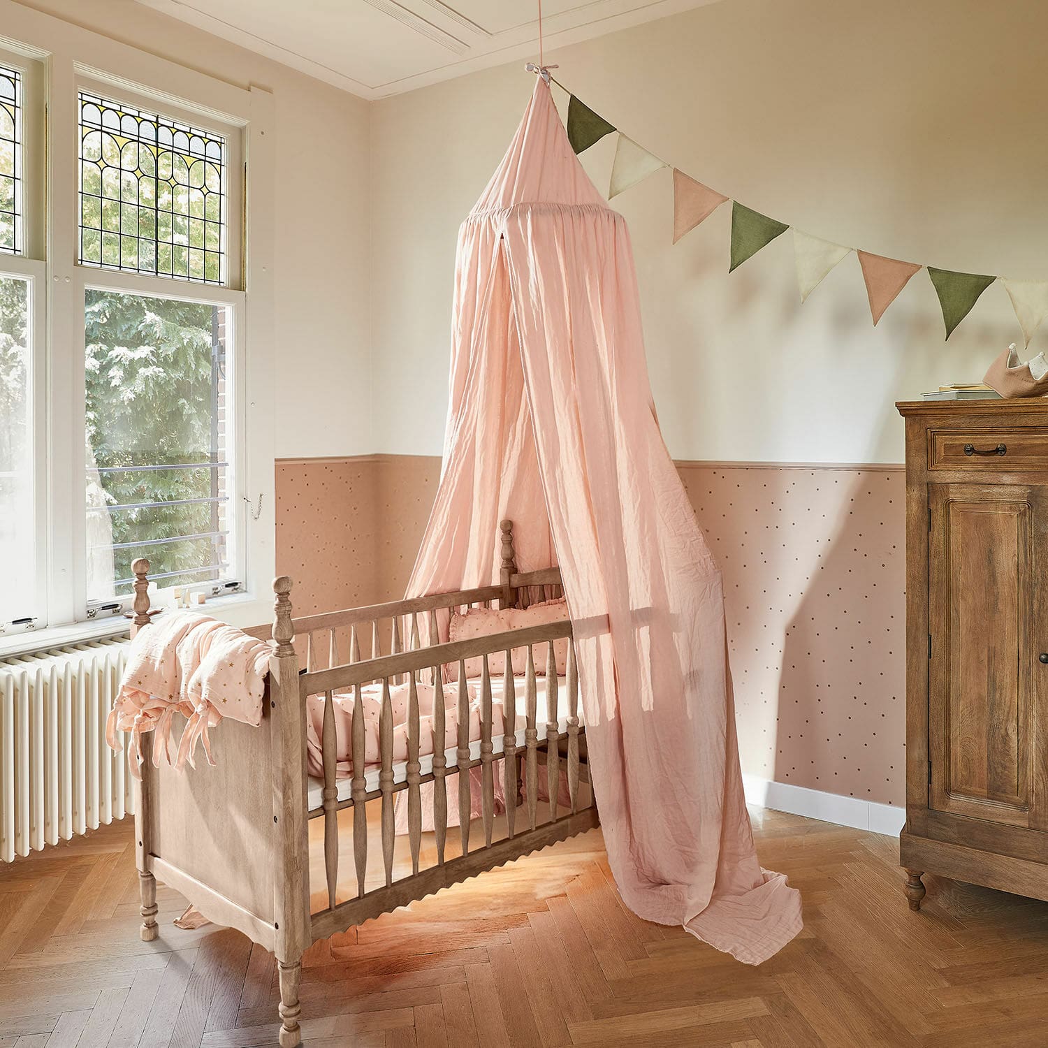 Babybett Merveillon Kinderbett aus Holz mit rosa Baldachin und passender Bettwäsche im pastellfarbenen Kinderzimmer