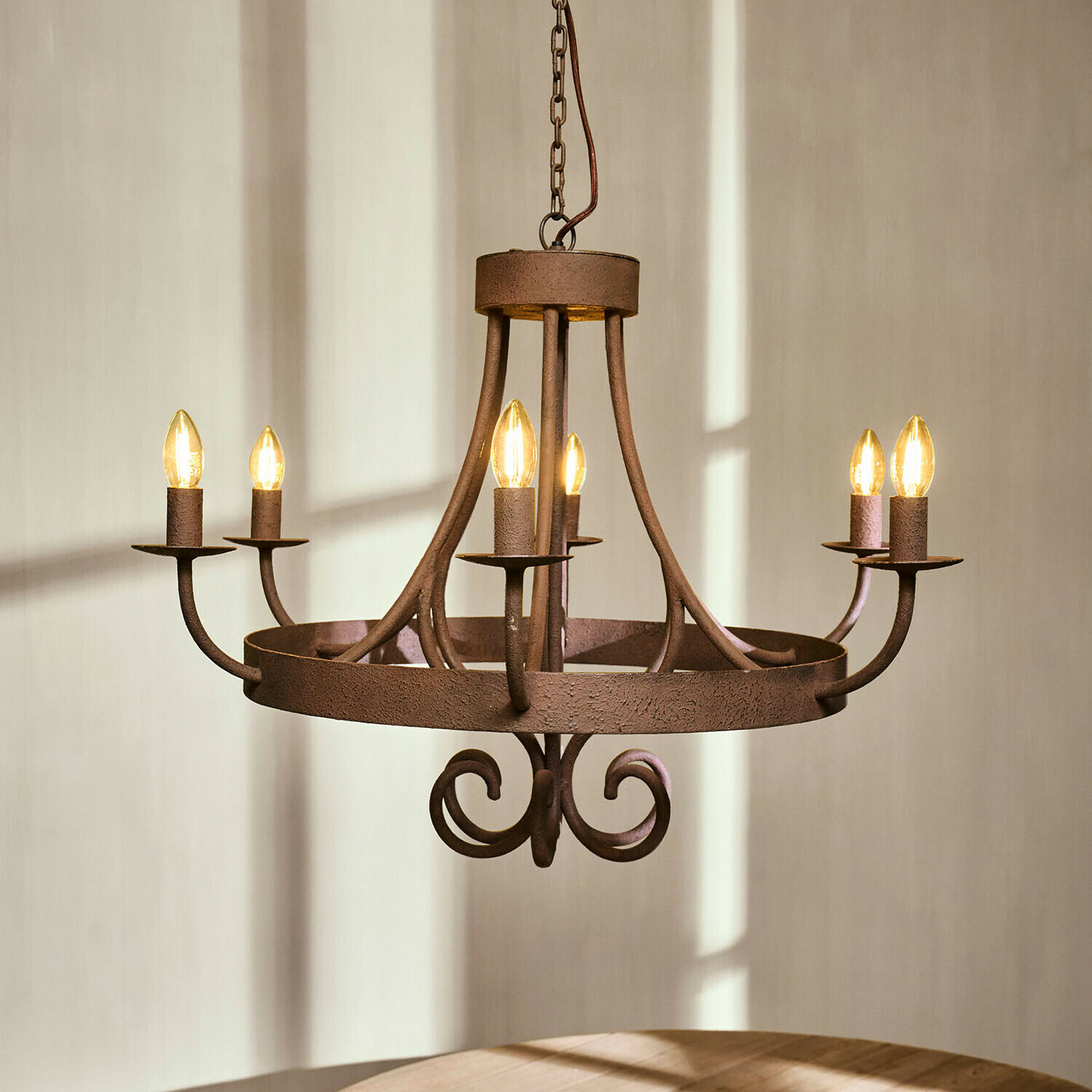 Rustikaler Metall-Kronleuchter in Rostfarbe mit sechs kerzenförmigen Leuchtmitteln, Innenbeleuchtung