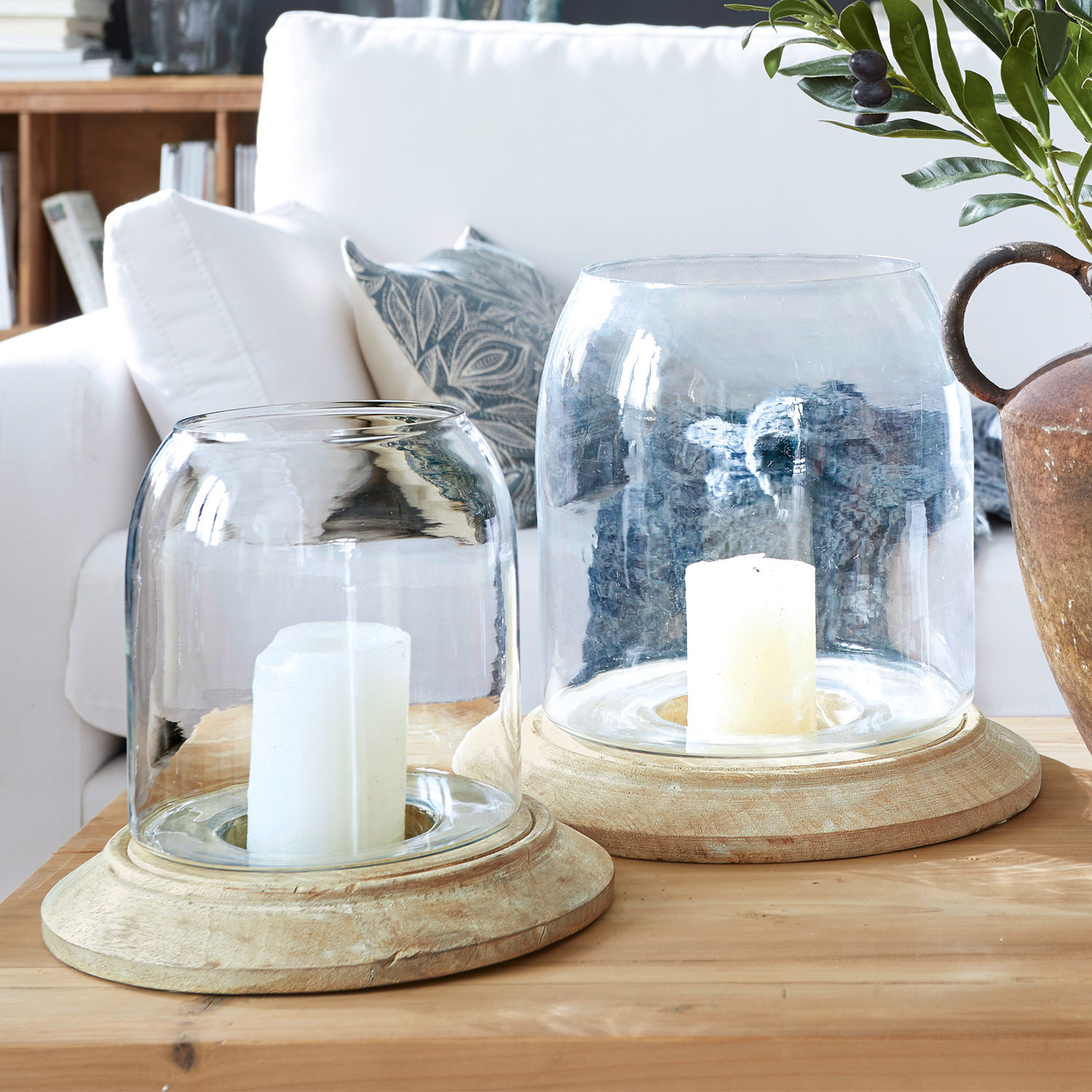 Windlicht 2er Set Bran Zwei Windlichter aus Glas und hellem Holz auf einem Holztisch im gemütlichen Wohnzimmer