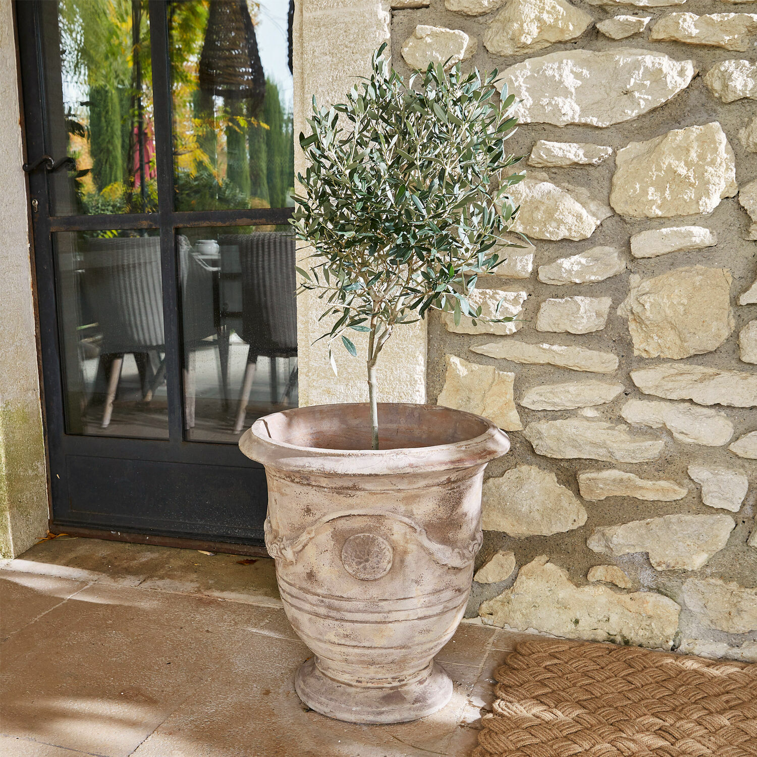 Übertopf Garwood Grosser dekorativer Terrakotta-Blumentopf in Beige mit grüner Pflanze auf der Terrasse