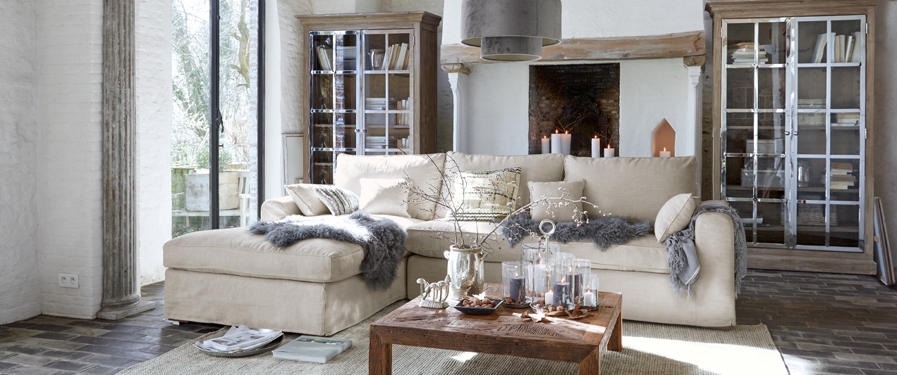 Beiges Ecksofa aus weichem Stoff im hellen Wohnzimmer mit Holztisch und Cheminée