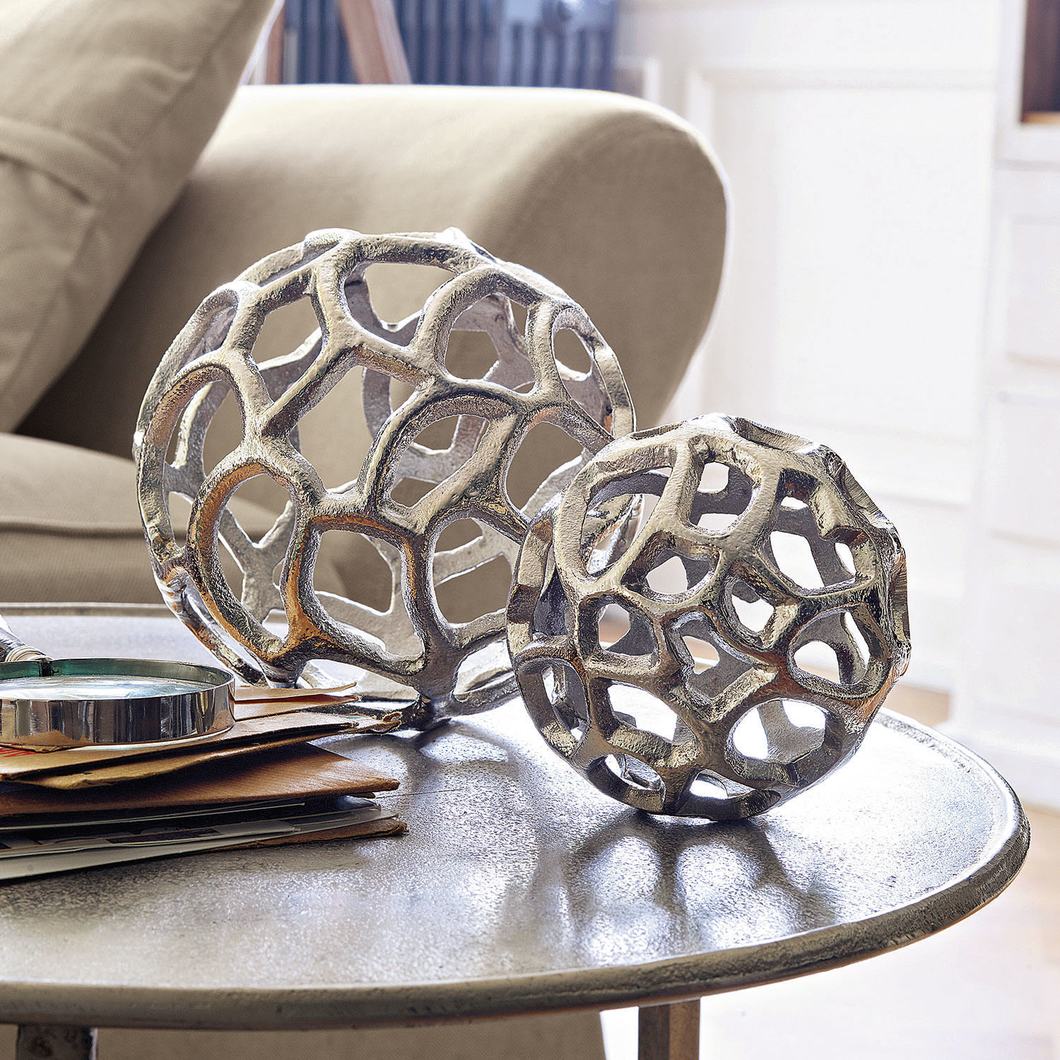 Deko-Objekt 2er Set Venay Dekorative silberne Metallkugeln mit offenem Design auf einem Wohnzimmer-Tisch