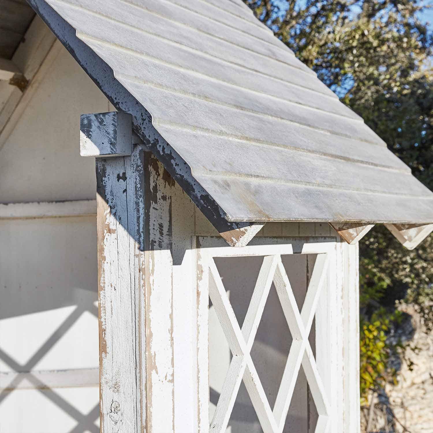 Weisses Holz-Gartenhaus mit abgenutztem Look und schrägem Dach im Außenbereich
