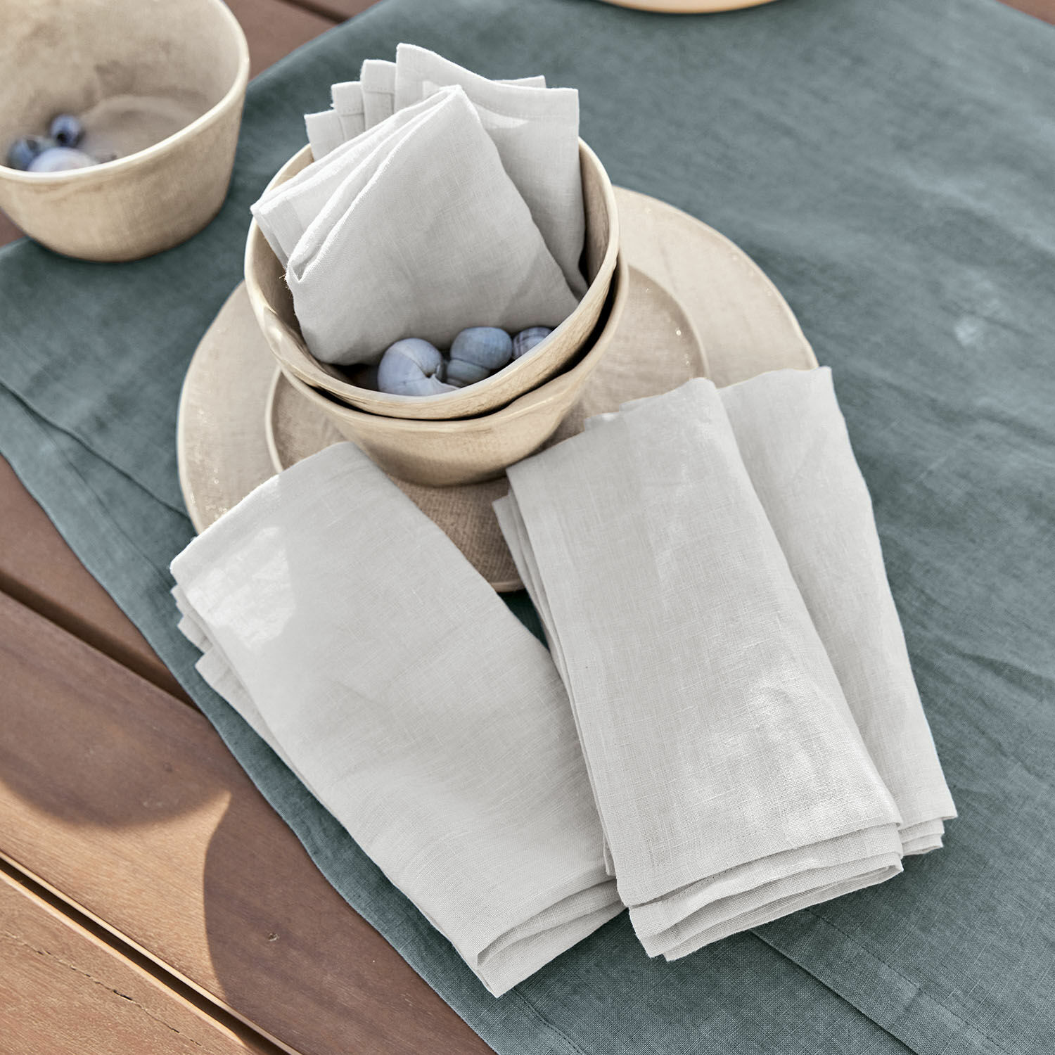Serviette 4er Set Ghis Weisse Leinenservietten auf grünem Tischtuch mit Keramikschalen und Dekokugeln