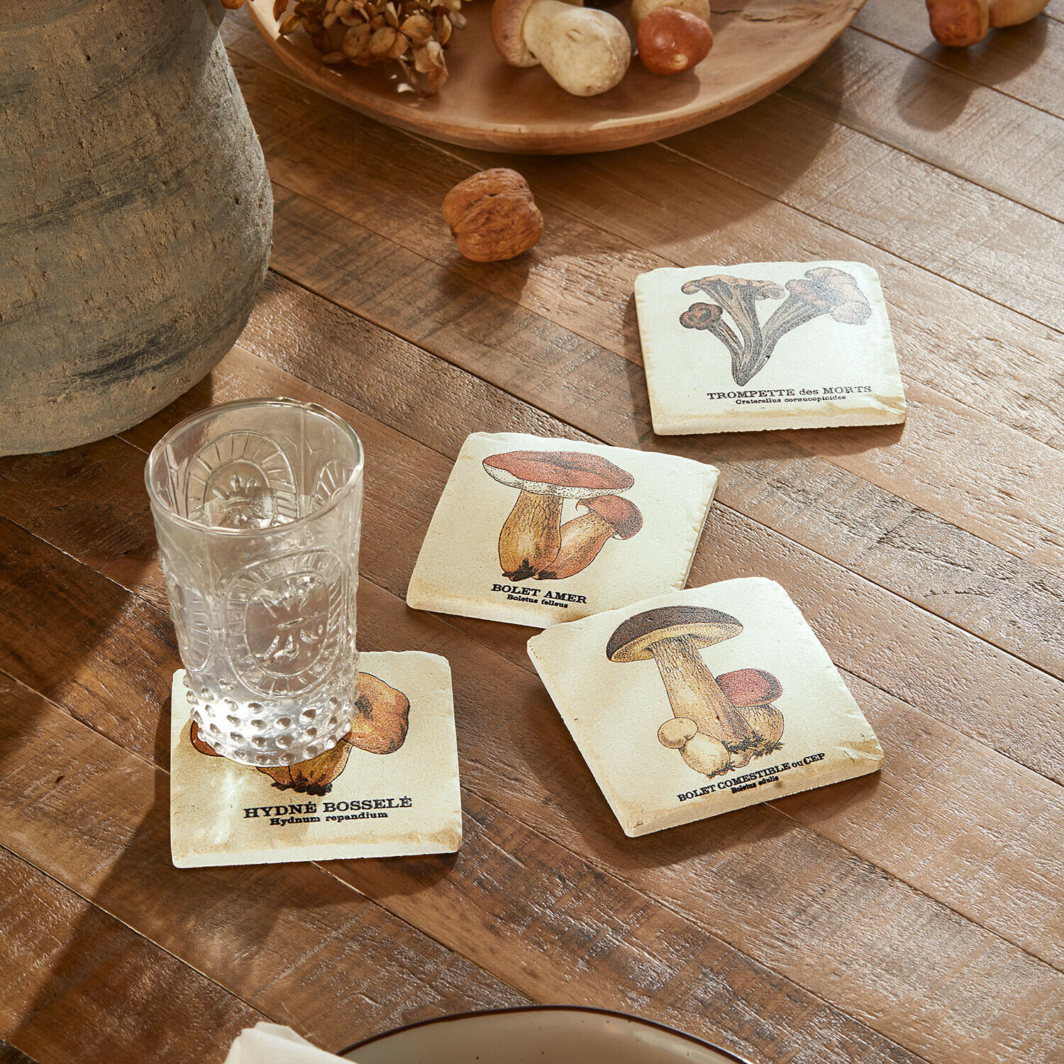 Untersetzer 4er Set Jandoria Untersetzer mit Pilzmotiven auf Holztisch mit klarem Glas und Walnüssen