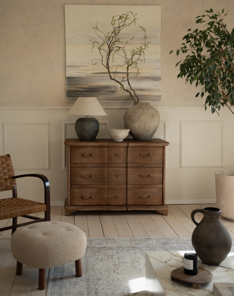 Holzkommode mit sechs Schubladen in Naturfarbe, dekorative Vasen und Lampe im Wohnzimmer