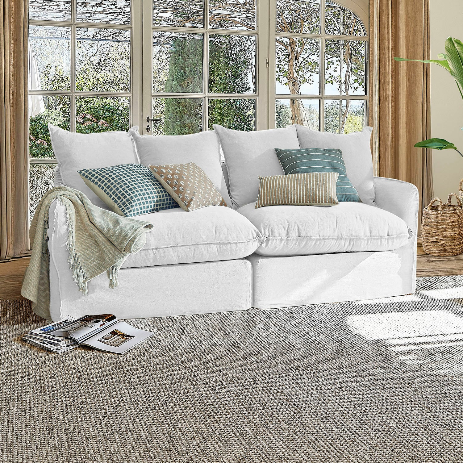 Sofa Dunswater Weisses Sofa aus Stoff mit gemusterten Kissen in hellem Wohnzimmer vor grossen Fenstern