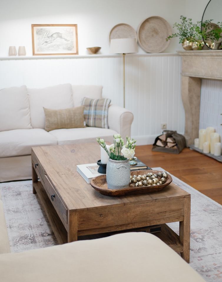 Wohnzimmer mit Holztisch und beigem Sofa, skandinavisch inspirierte Dekorationen
