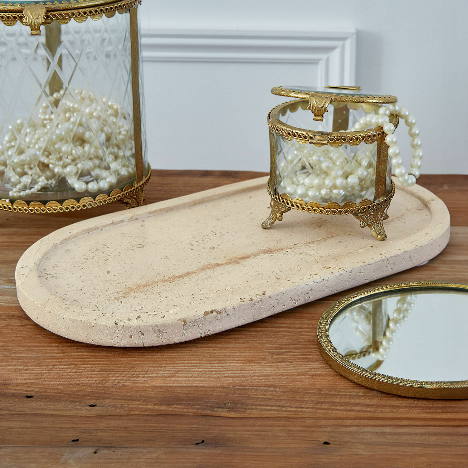 Schale Thalina Glas-Schmuckdose mit Messingrahmen und Perlen auf beigem Steintablett auf Holztisch