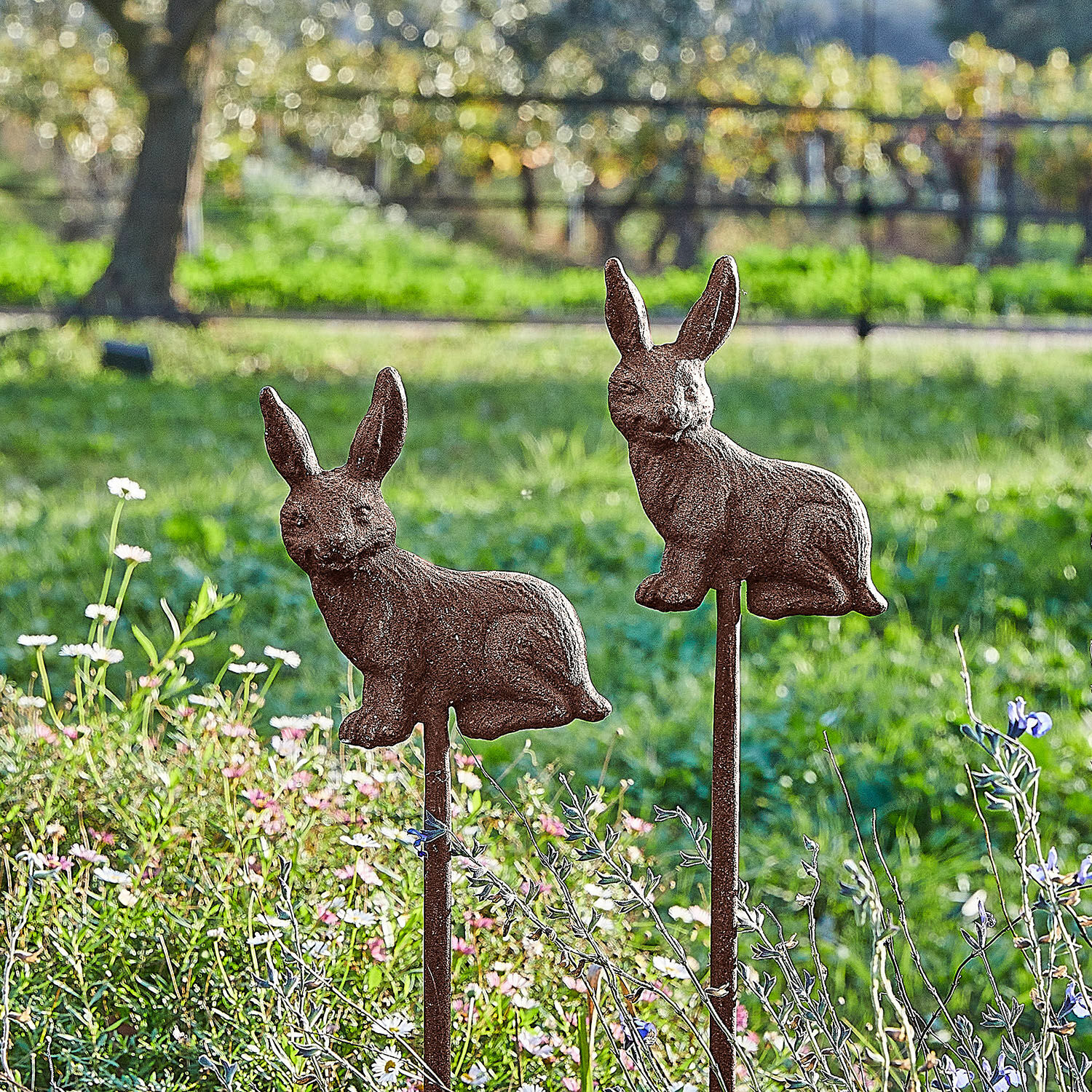 Gartenstab 2er Set Dariyah Dekorative Gartenstäbe mit rostigen Metallhasen vor grünem Hintergrund mit Blumen