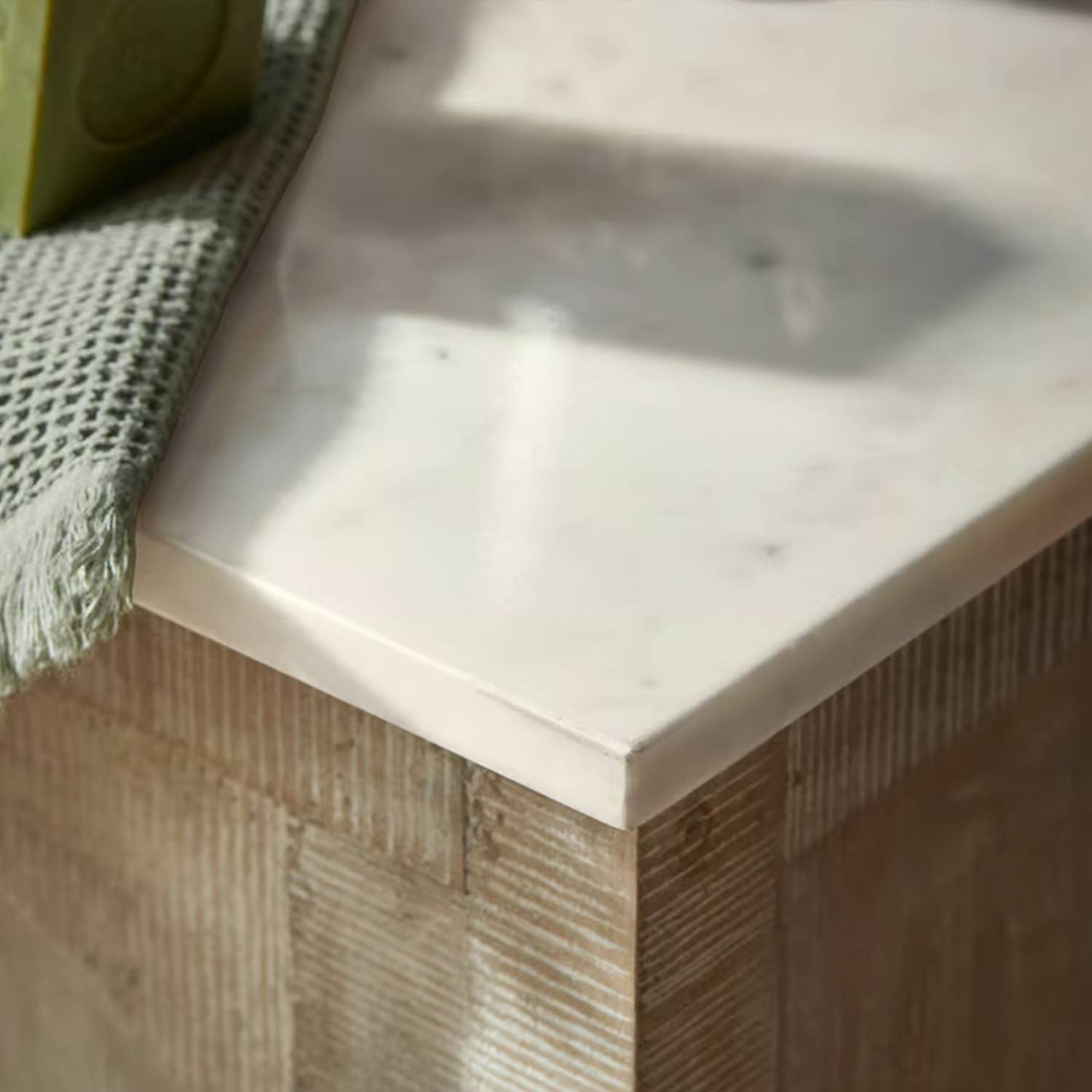 Weisse Marmorarbeitsplatte auf Holzunterbau mit grünem Stofftuch, moderner Möbelstil