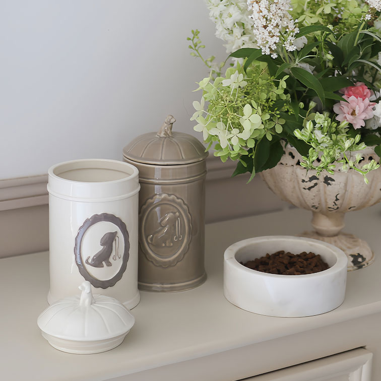 Keramikdosen in Creme und Beige für Hundefutter neben weisser Futterschale und Blumenarrangement