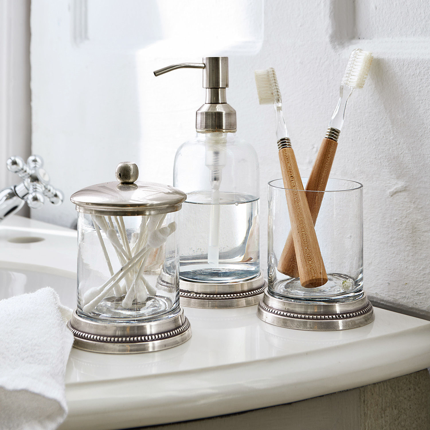 Bad-Set Drinapoly Glas-Badezimmeraccessoires mit Metallakzenten auf weissem Waschbecken mit Bambuszahnbürsten