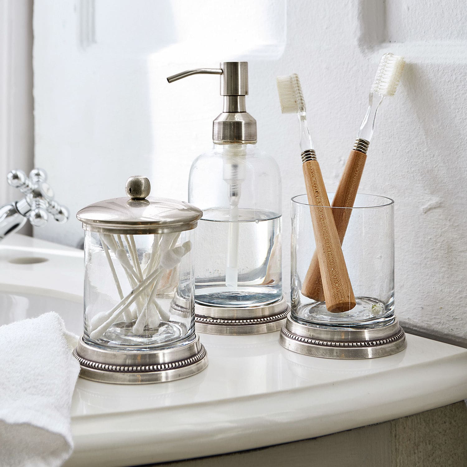 Bad-Set Drinapoly Glas-Badezimmeraccessoires mit Metallakzenten auf weissem Waschbecken mit Bambuszahnbürsten