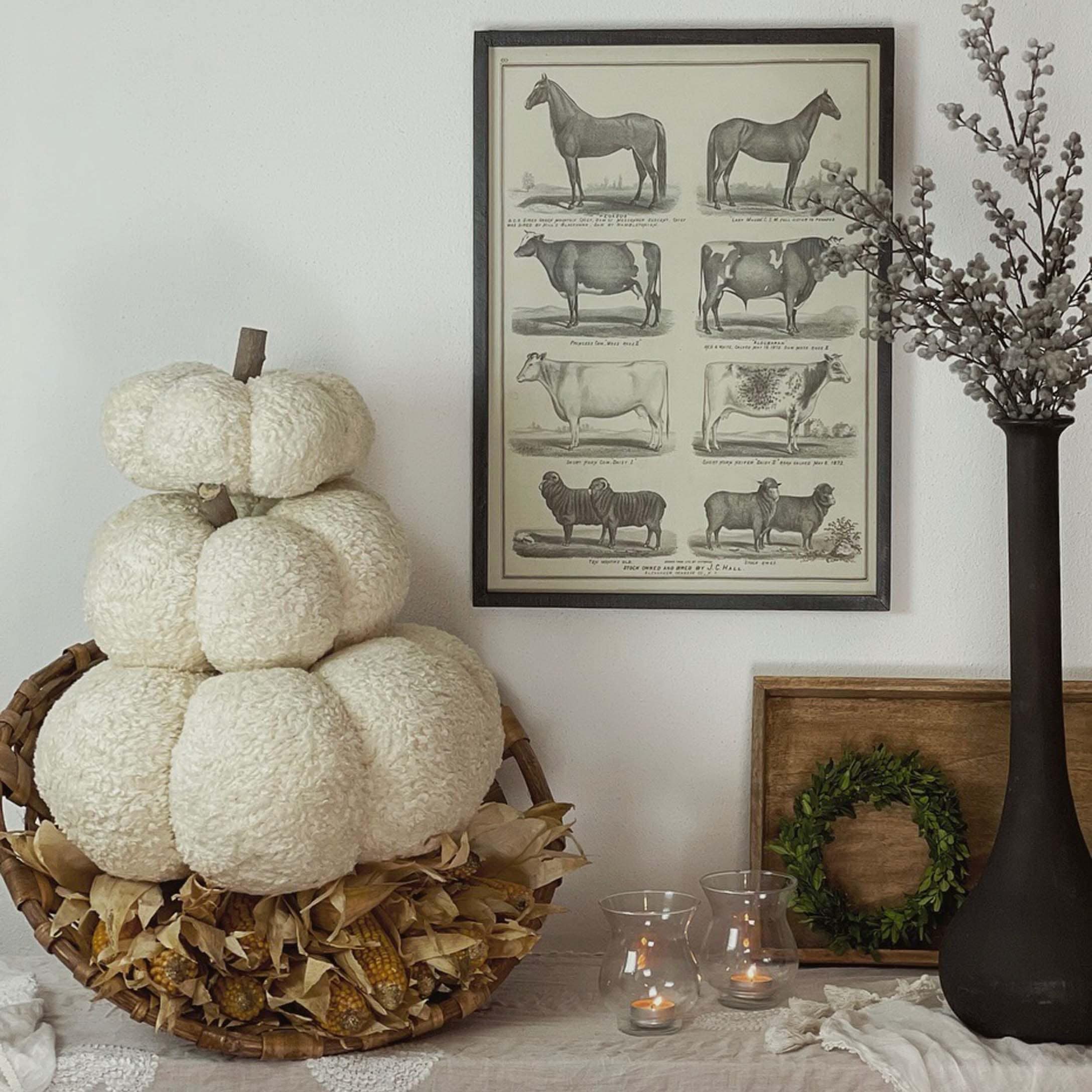 Herbstliche Dekoration mit weissem Plüschkürbis im Korb und Kerzen auf dem Tisch
