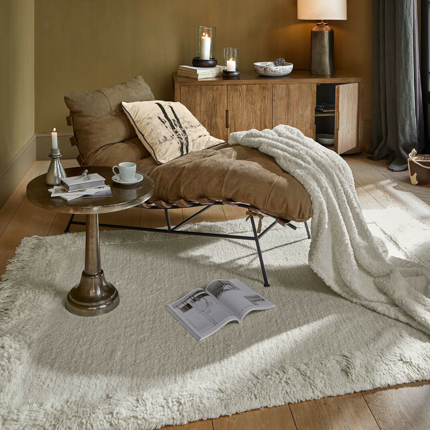 Brauner Ledersessel mit weisser Decke auf cremefarbenem Teppich in gemütlichem Wohnzimmer