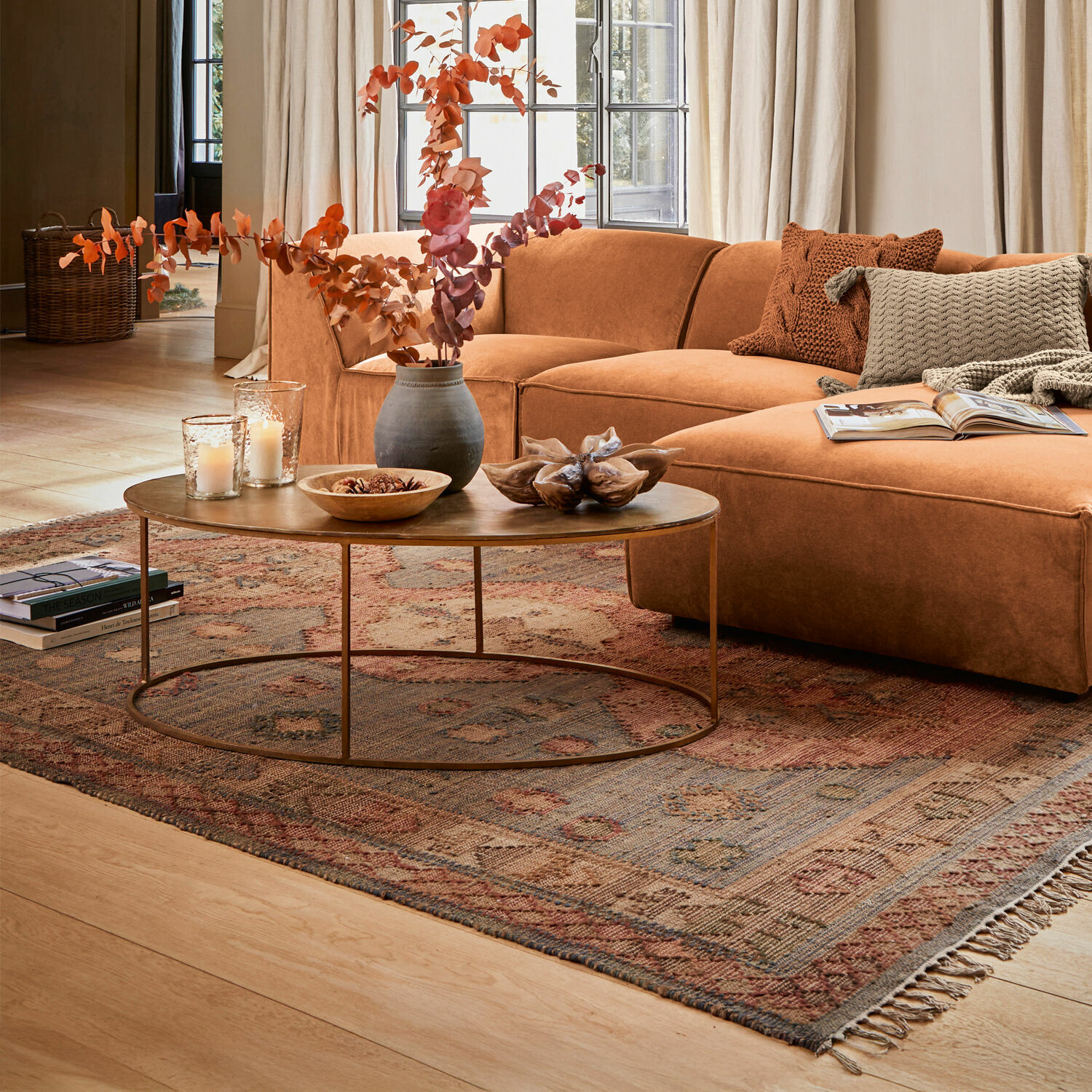 Braunes Ecksofa aus weichem Stoff auf gemustertem Teppich in hellem Wohnzimmer mit grossen Fenstern