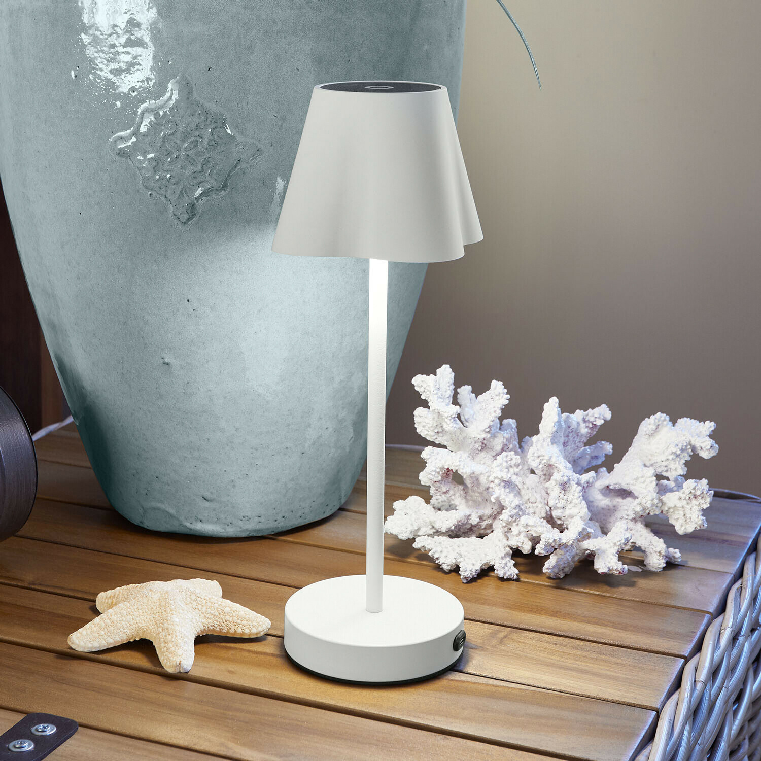 Weisse Metall-Tischlampe mit Lampenschirm auf Holztisch mit maritimer Dekoration