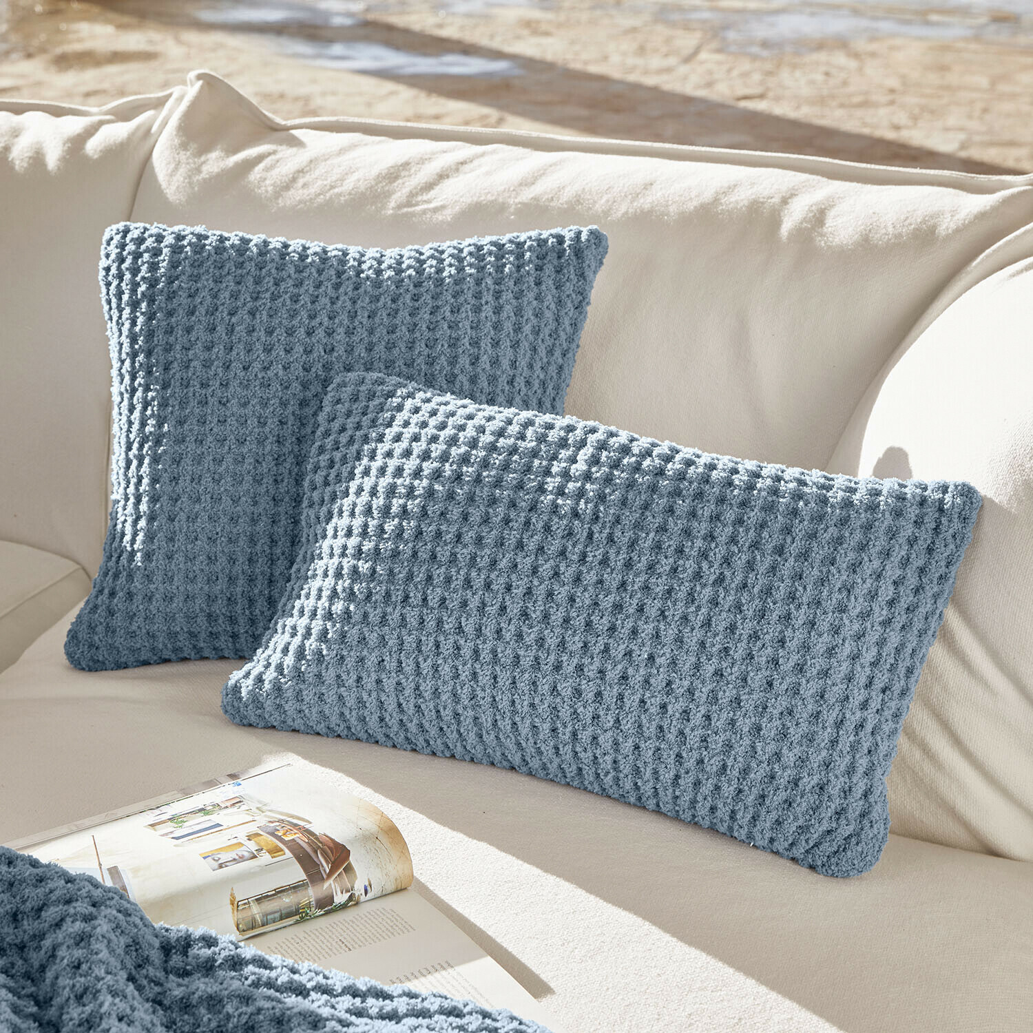 Zwei blaue Strickkissen auf cremefarbenem Sofa, weiche Wohnaccessoires für gemütliches Wohnzimmer