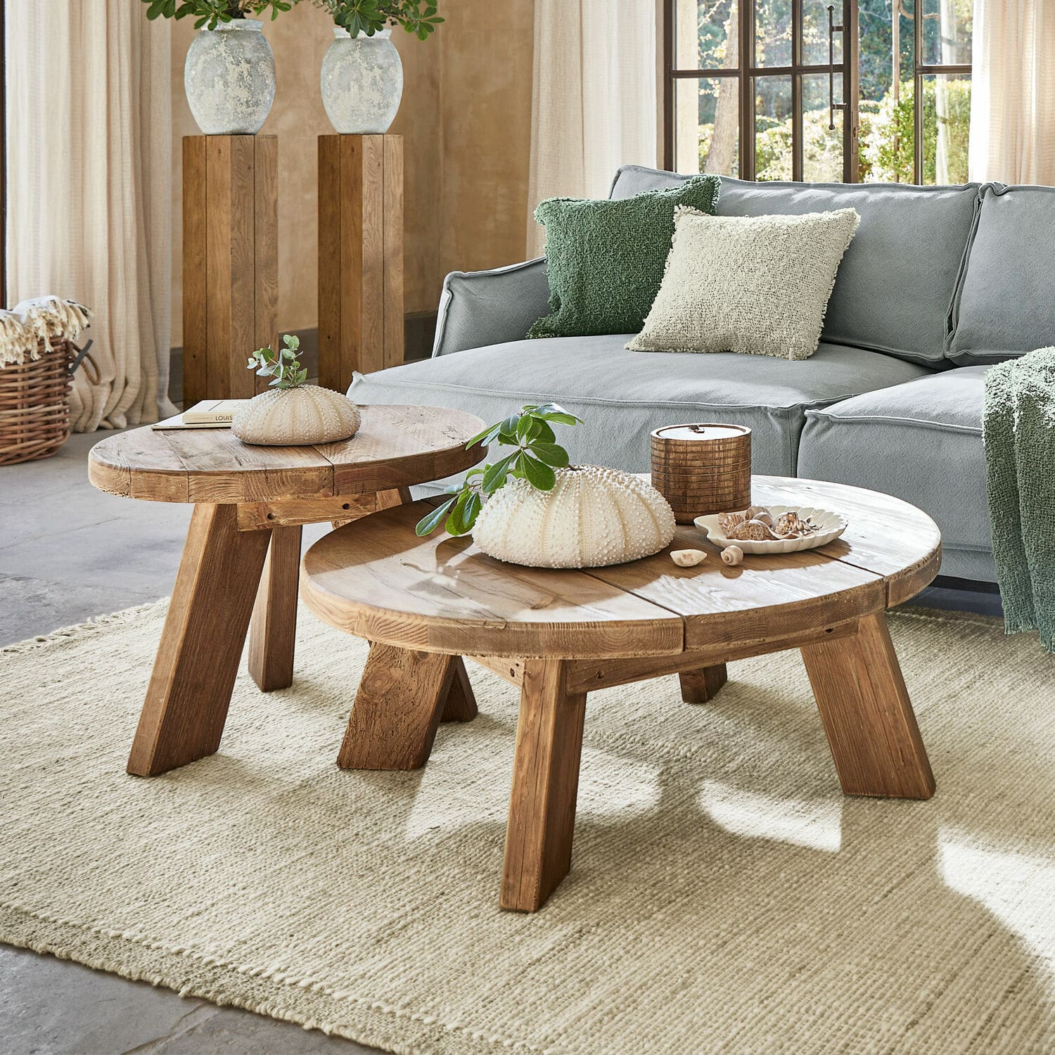 Couchtisch 2er Set Oteley Zwei runde Couchtische aus Holz in Naturfarbe auf hellem Teppich vor grauem Sofa im Wohnzimmer
