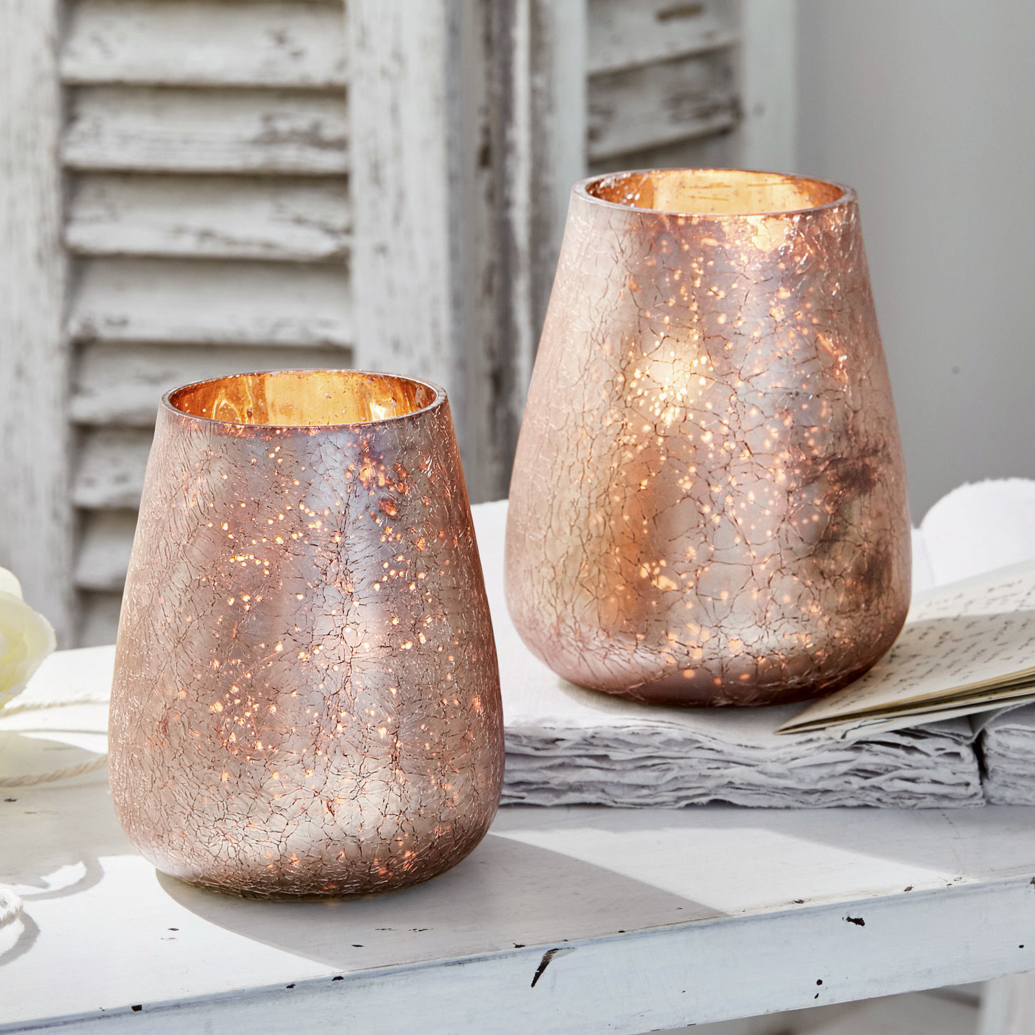 Windlicht 2er Set Chanut Zwei dekorative Windlichter aus kupferfarbenem Glas mit Risseffekt auf weissem Tisch