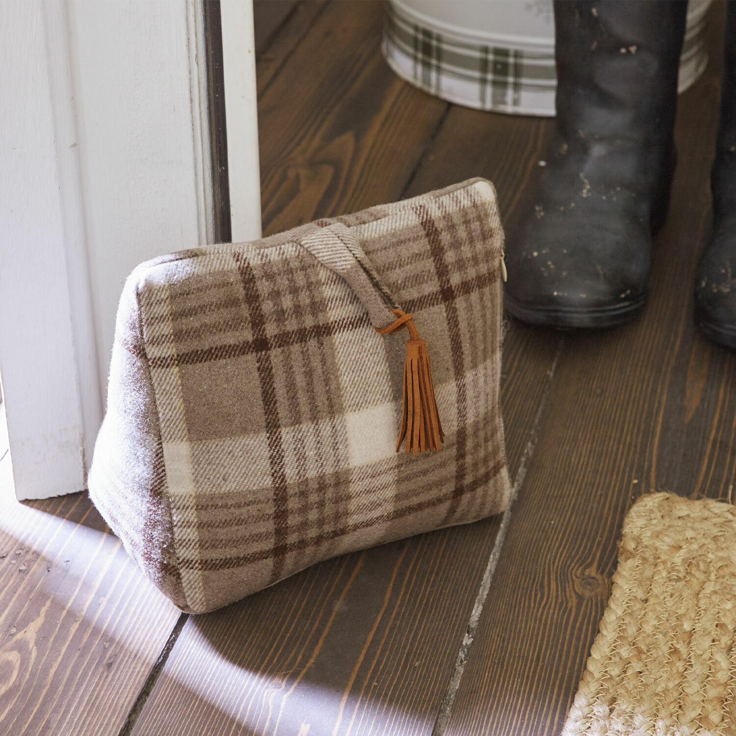 Türstopper Ersac Beige karierte Tasche aus weichem Stoff mit braunem Quastenanhänger auf Holzboden