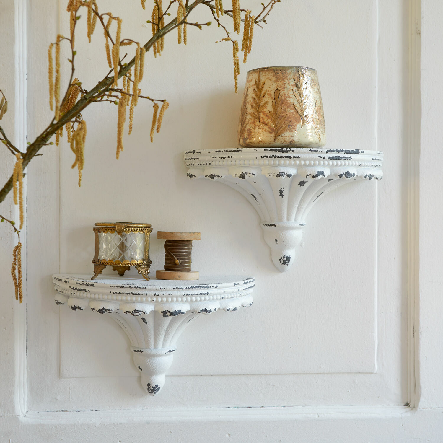 Zwei weisse Wandregale aus antikem Metall mit dekorativen Vintage-Objekten an der Wand