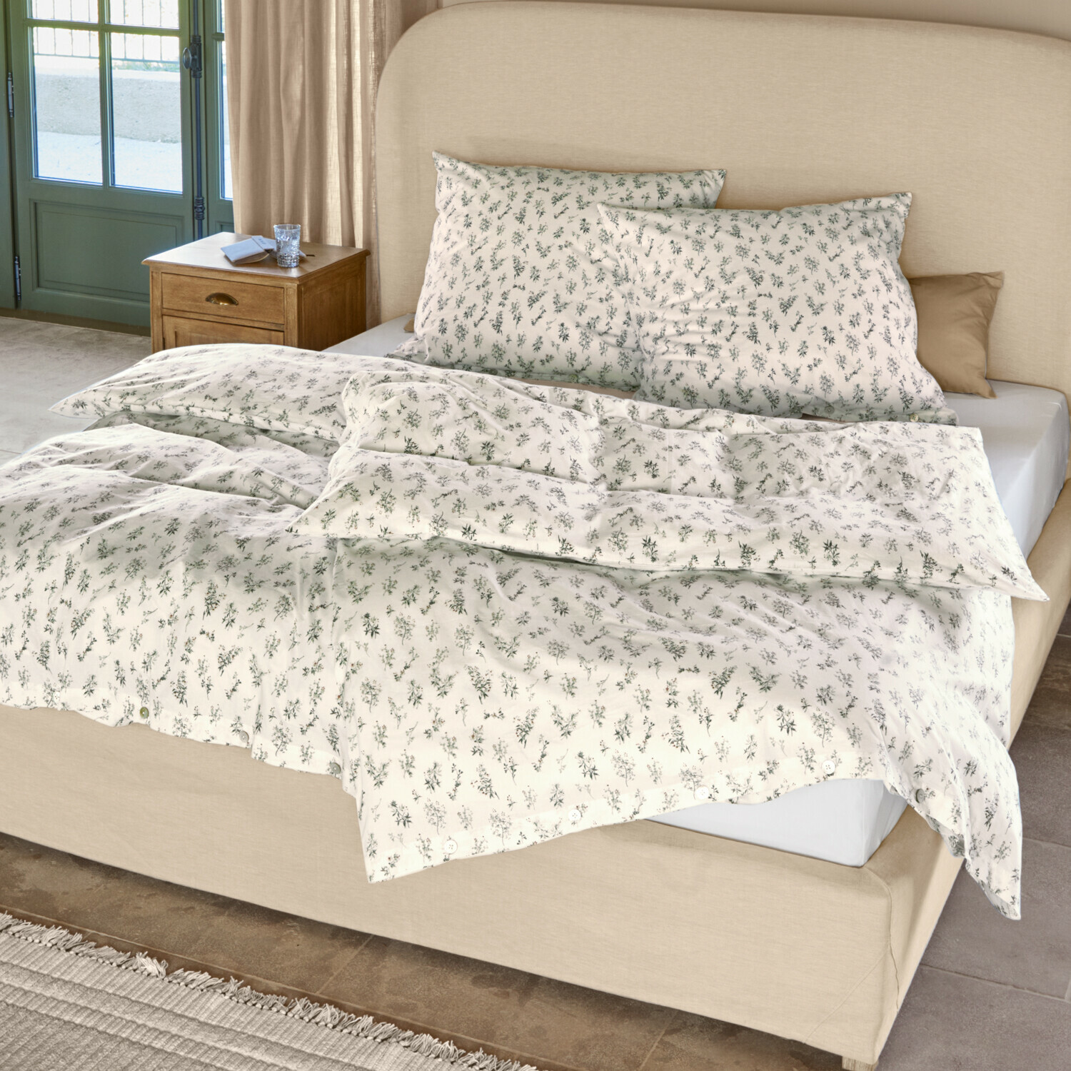 Baumwoll-Bettwäsche in Creme mit zartem grünem Pflanzenmuster auf Bett mit beigem Kopfteil