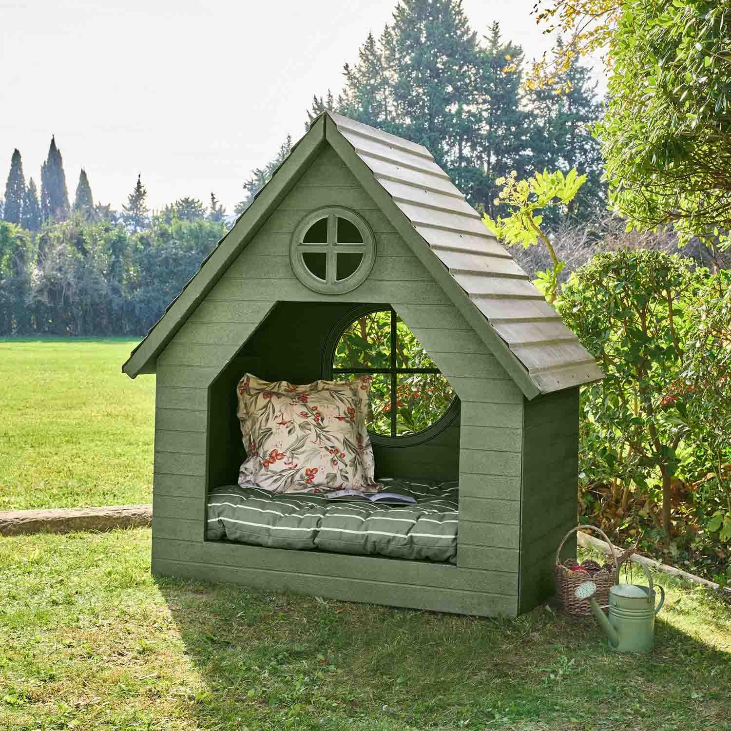 Grünes Holz-Gartenhaus mit Kissen und rundem Fenster, ideal zum Entspannen im Freien