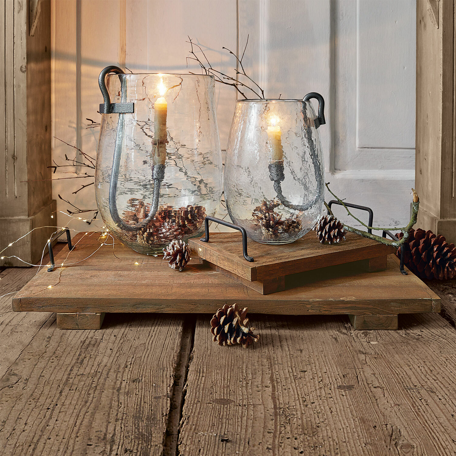 Tablett 2er Set Conner Glasslaternen mit Metallgriffen auf Holztablett, dekoriert mit Tannenzapfen und brennenden Kerzen