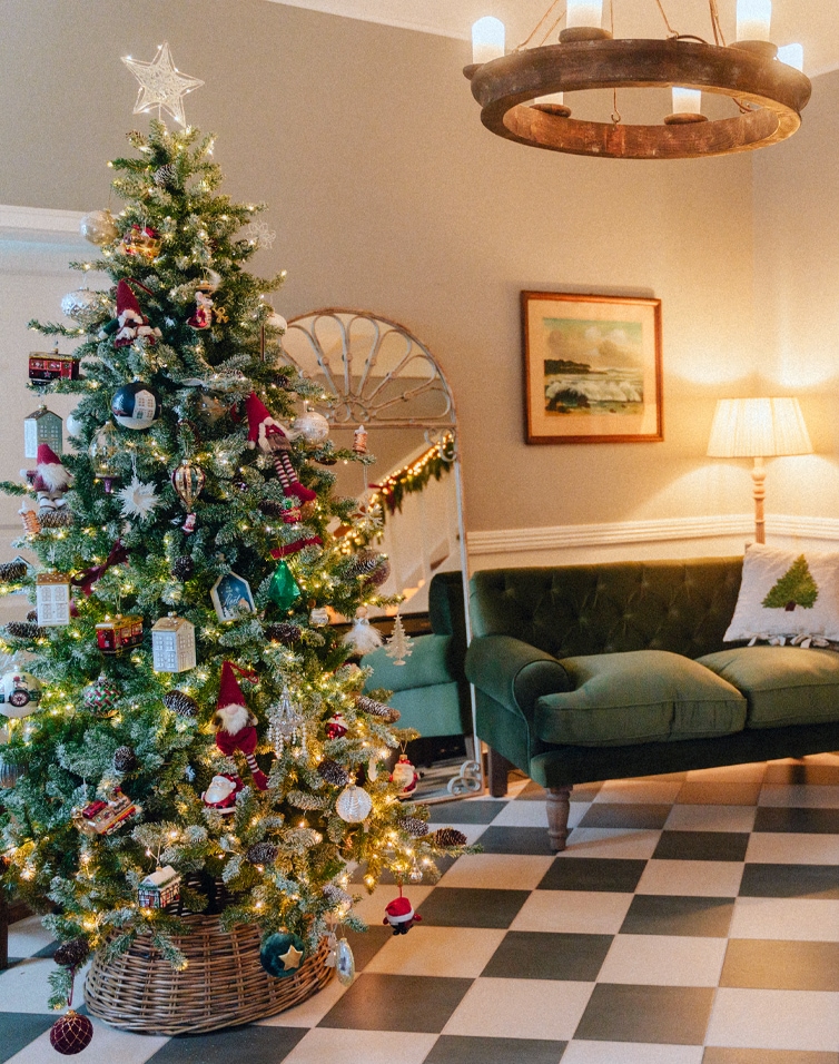 Gemütliches Wohnzimmer mit grünem Sofa und festlich geschmücktem Christbaum für Weihnachtsstimmung