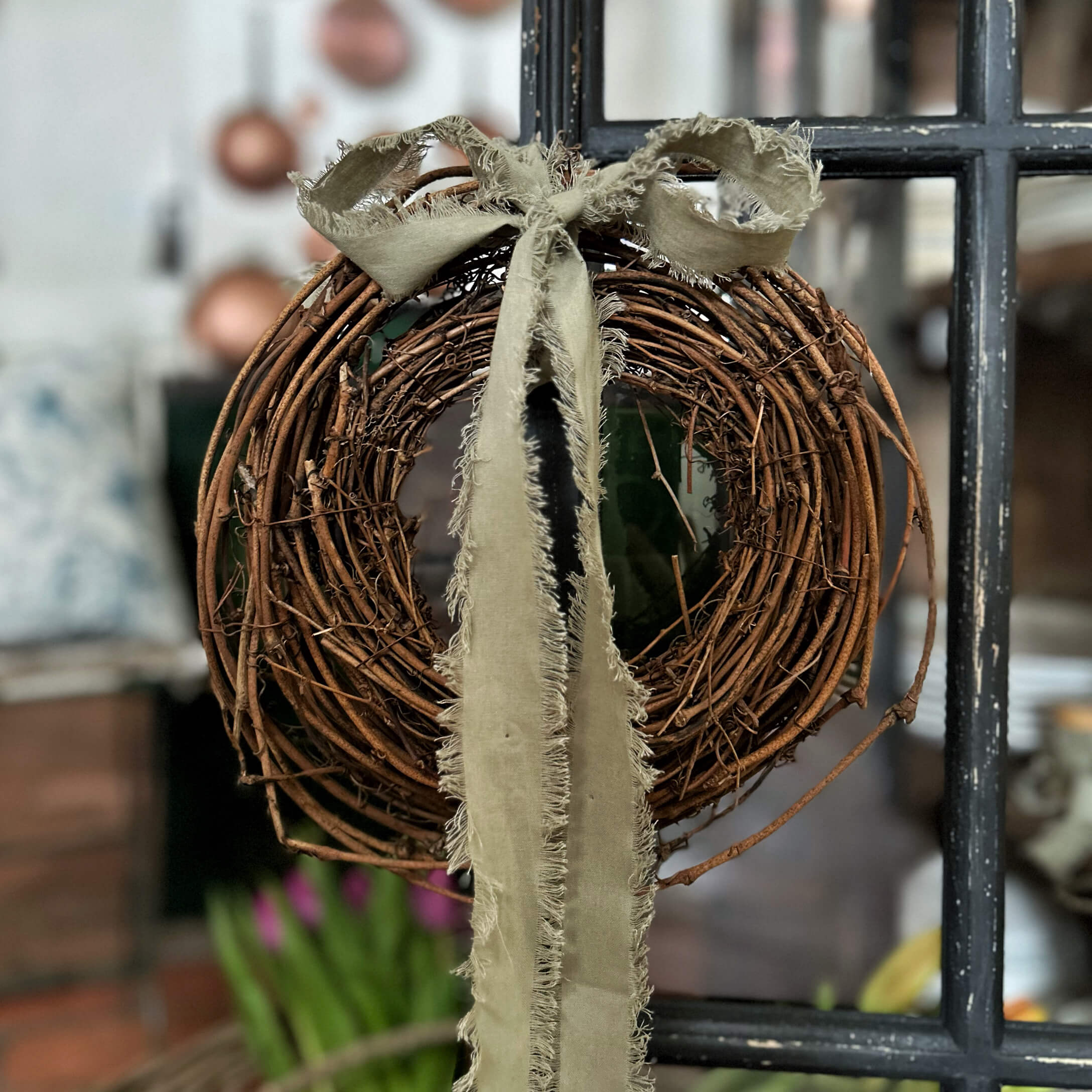 Dekorativer Kranz aus Naturzweigen mit beigem, ausgefranstem Band für Wohnraumdekoration