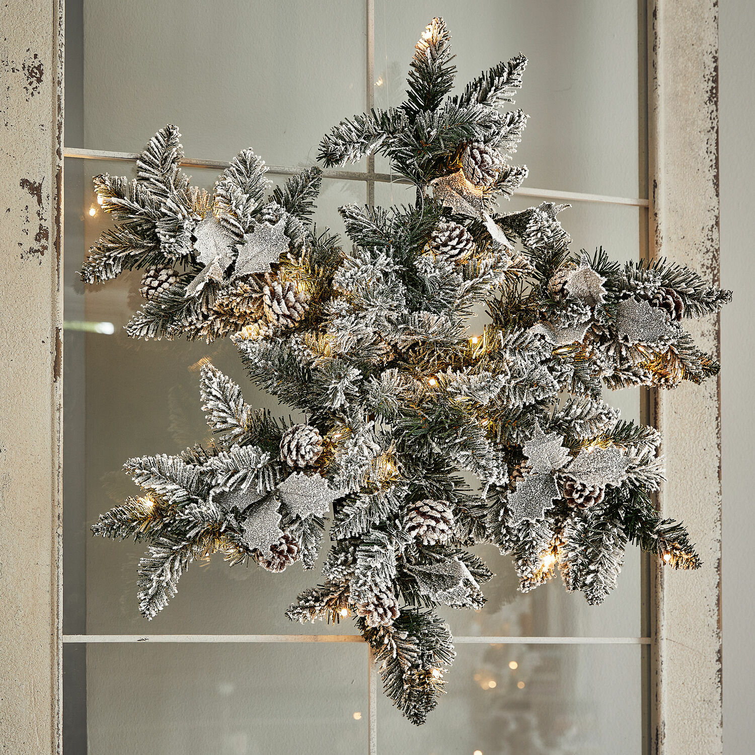 LED-Schneeflocke Azimara Weihnachtsstern aus grünen Zweigen mit Schneeeffekt, Zapfen und warmweissen LED-Lichtern als Dekoration