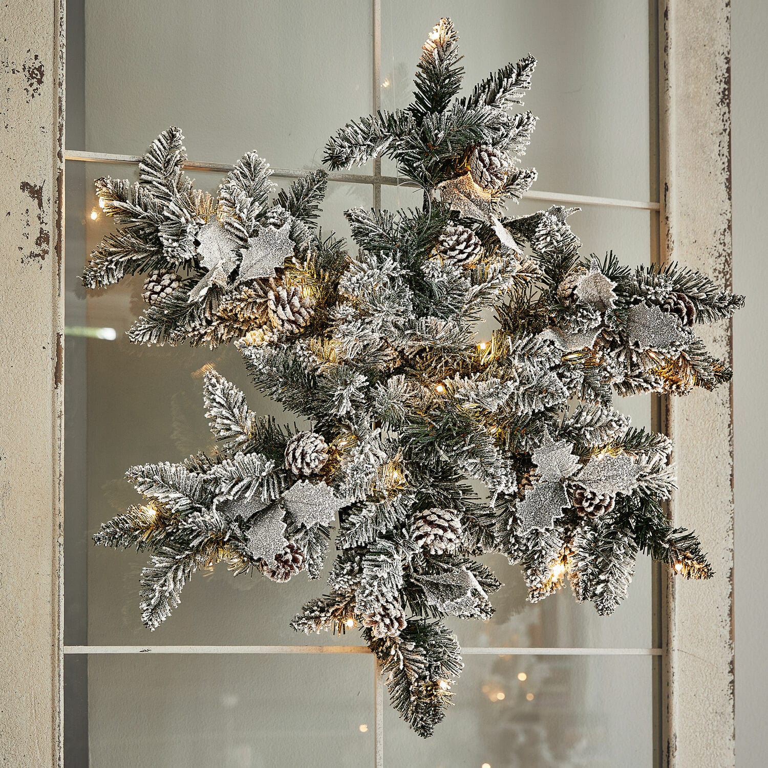LED-Schneeflocke Azimara Weihnachtsstern aus grünen Zweigen mit Schneeeffekt, Zapfen und warmweissen LED-Lichtern als Dekoration
