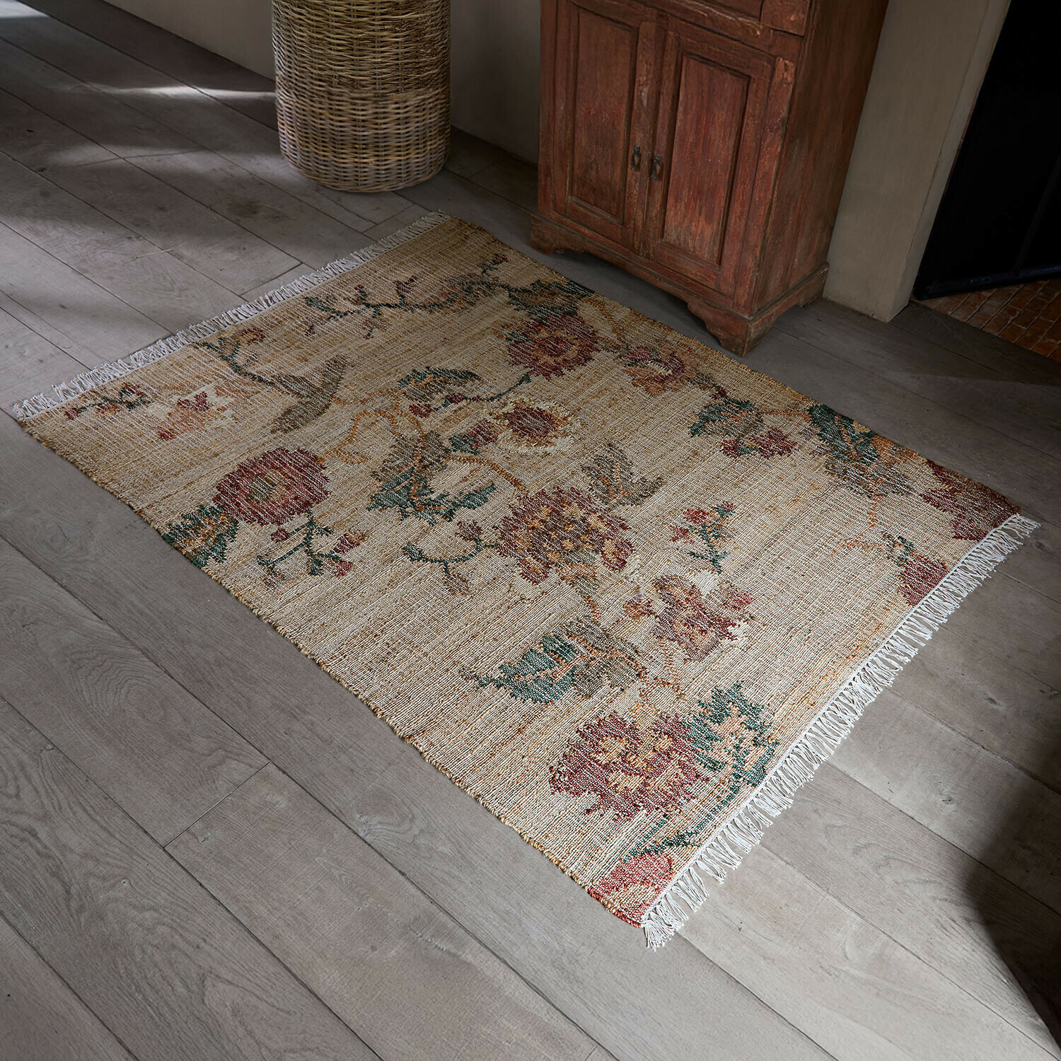 Teppich Caléndoro Beiger Teppich aus Naturmaterial mit Blumenmuster und Fransen auf hellem Holzboden