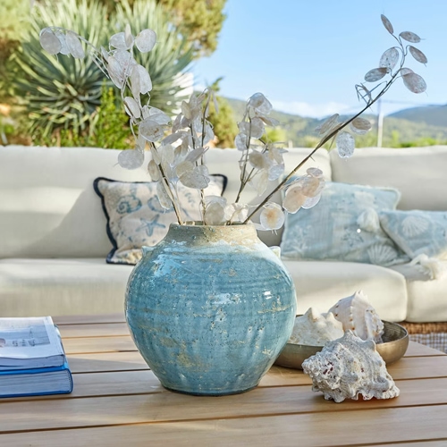 Blaue Keramikvase auf Holztisch mit getrockneten Pflanzen und Muscheln, stilvolle Wohnraumdekoration