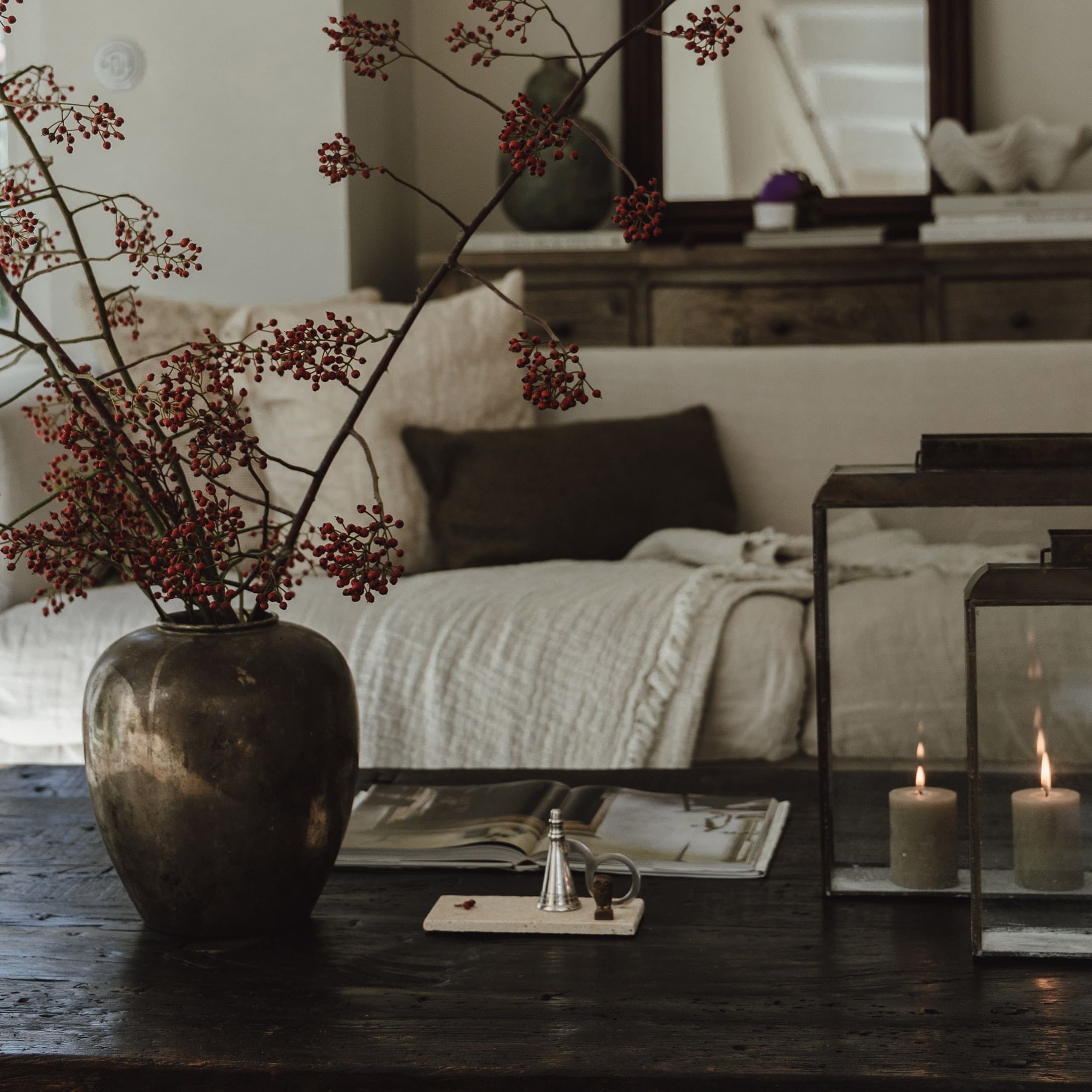 Dekorative Vase mit roten Zweigen auf dunklem Holztisch im gemütlichen Wohnzimmer