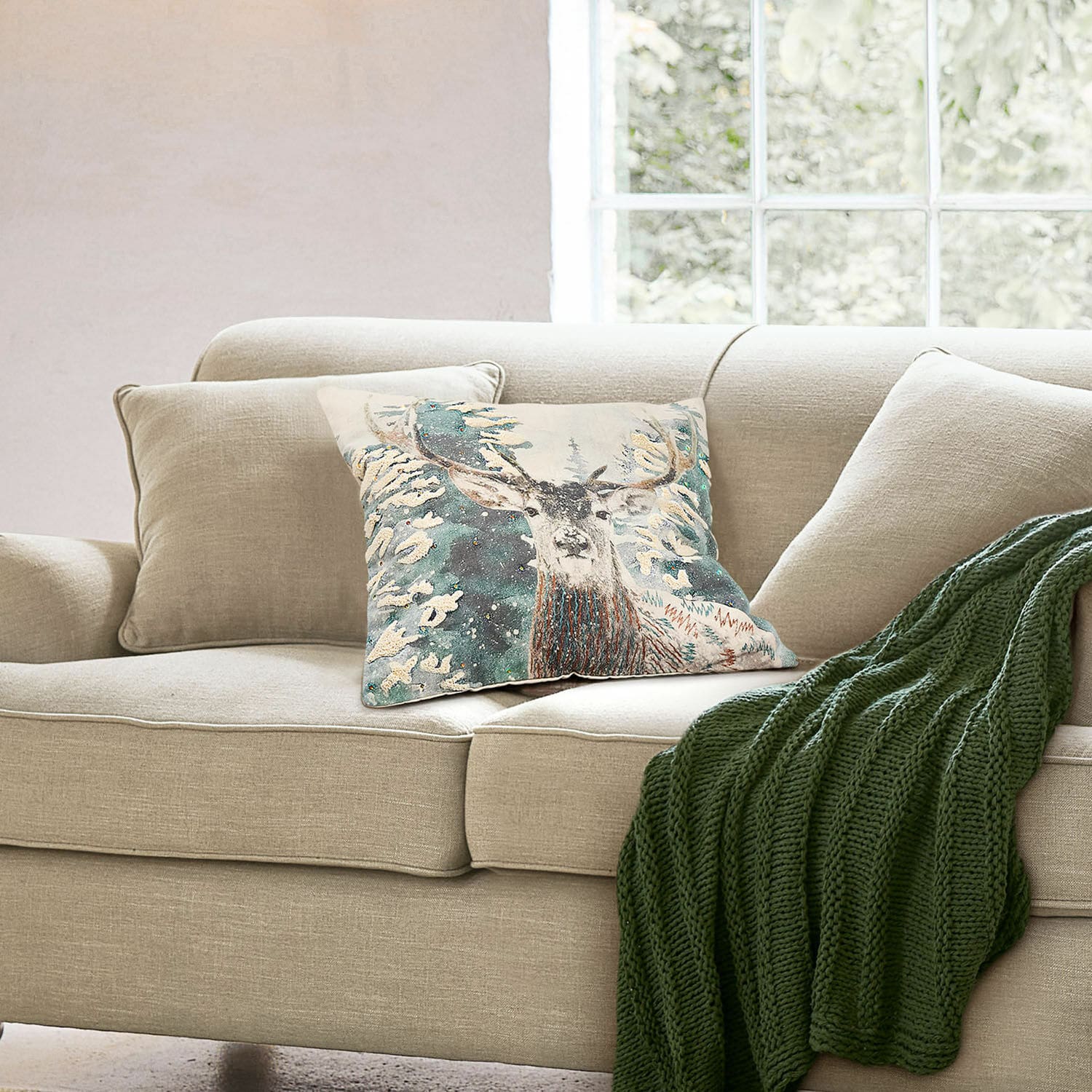 Kissenhülle Elvaris Beiges Sofa mit dekorativem Hirschkissen und grünem Strickplaid in hellem Wohnzimmer