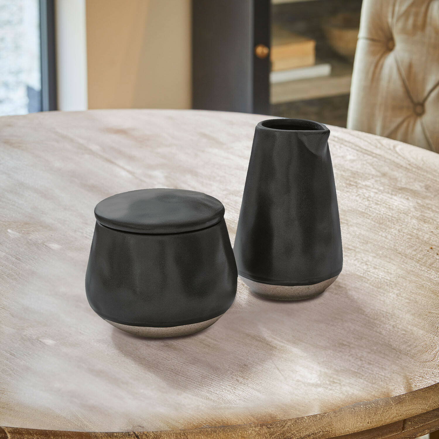 Schwarzer Keramikkrug und Behälter auf blau-weiss gefliestem Tisch, moderne Küchengefässe